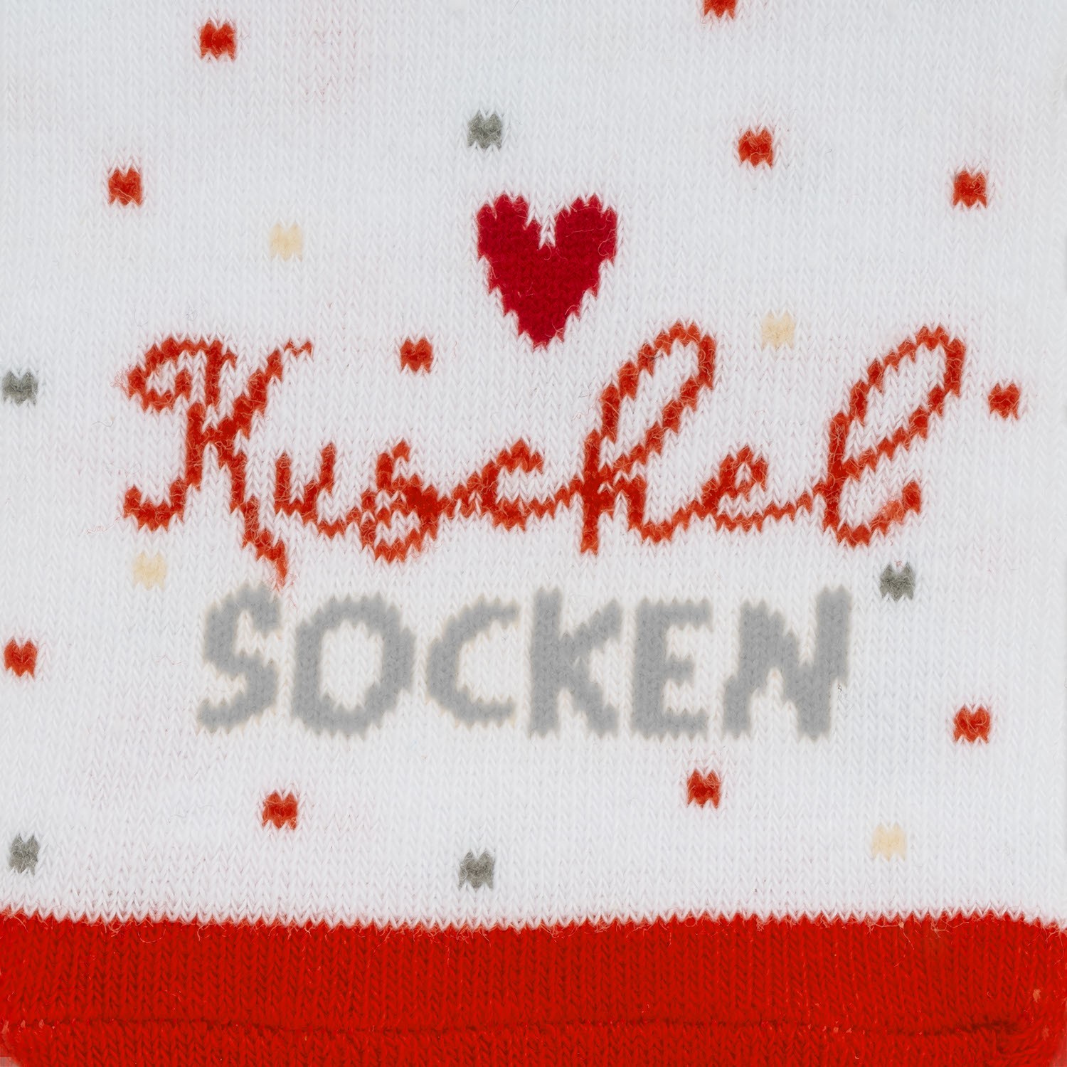 Weiße Stricksocke mit rotem Schriftzug 'Kuschelsöckchen' und Herzmotiven