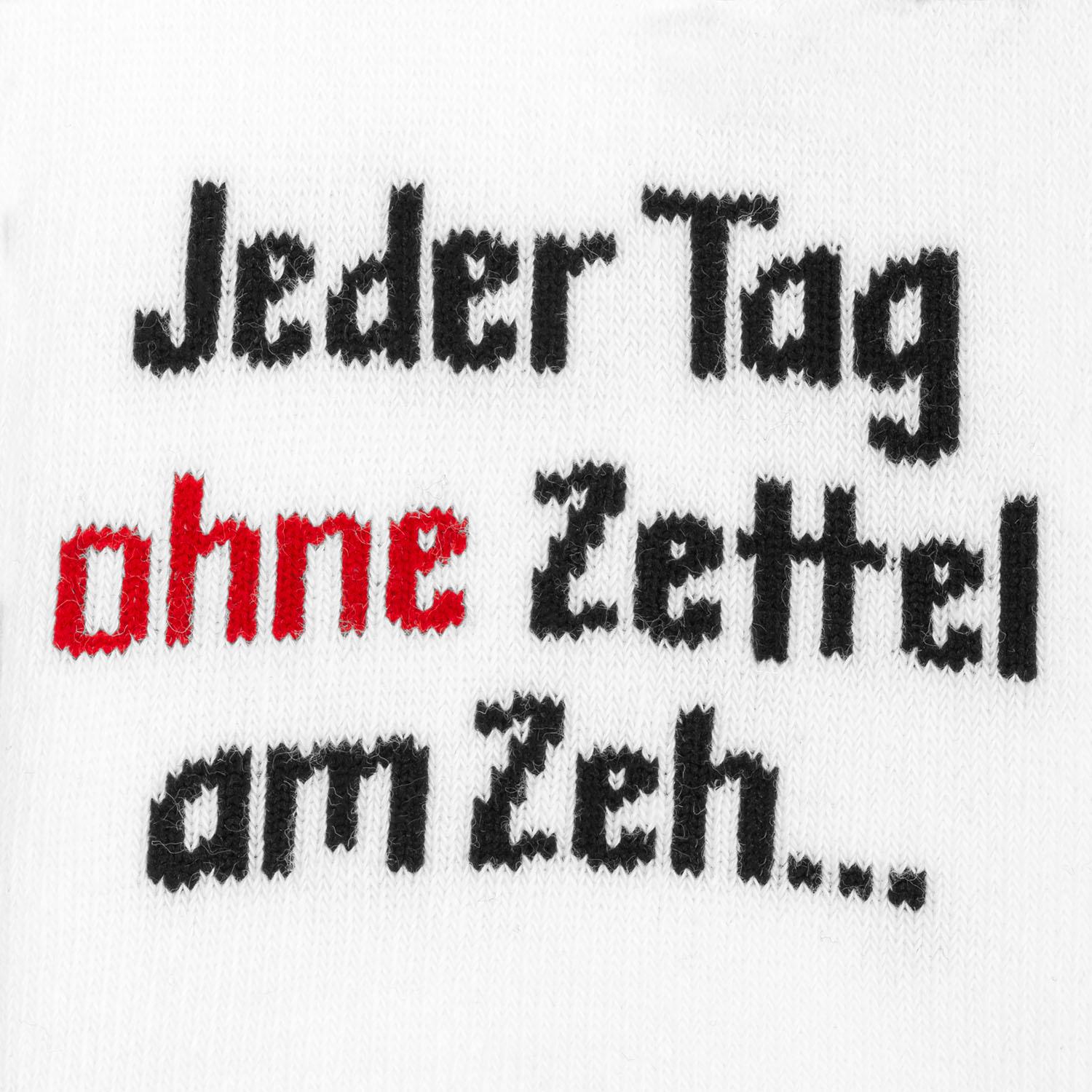 Weiße Socke mit schwarzem Schriftzug und rotem Akzent, Stickerei auf weißem Stoff.