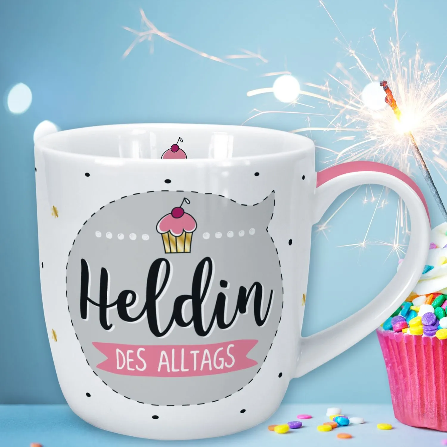 Weiße Porzellantasse mit grauem Kreis und dem Schriftzug Heldin des Alltags sowie pinkem Henkel