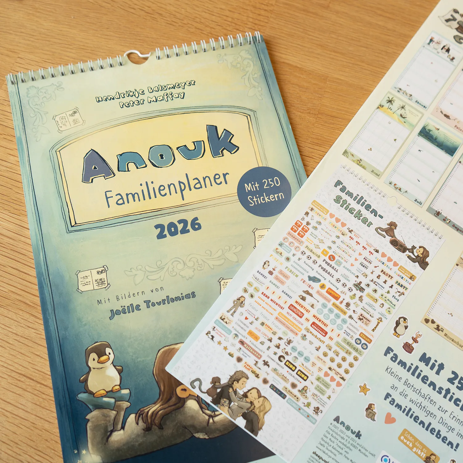 Blauer Anouk Familienplaner 2026 mit Stickerbogen, Spiralbindung und Pastellmotiv.