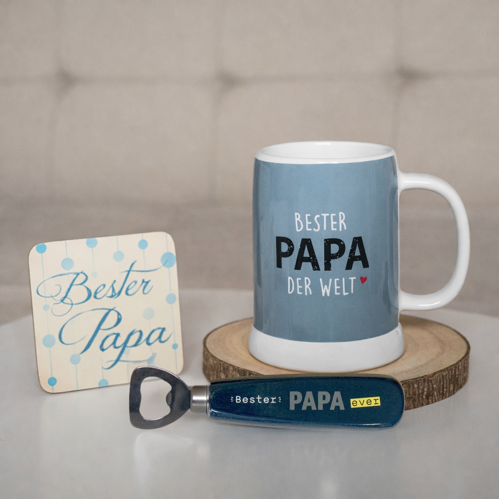 Blauer Keramik-Becher mit Spruch 'Bester Papa der Welt' und Beilage aus Flaschenöffner, Untersetzer und Karte.