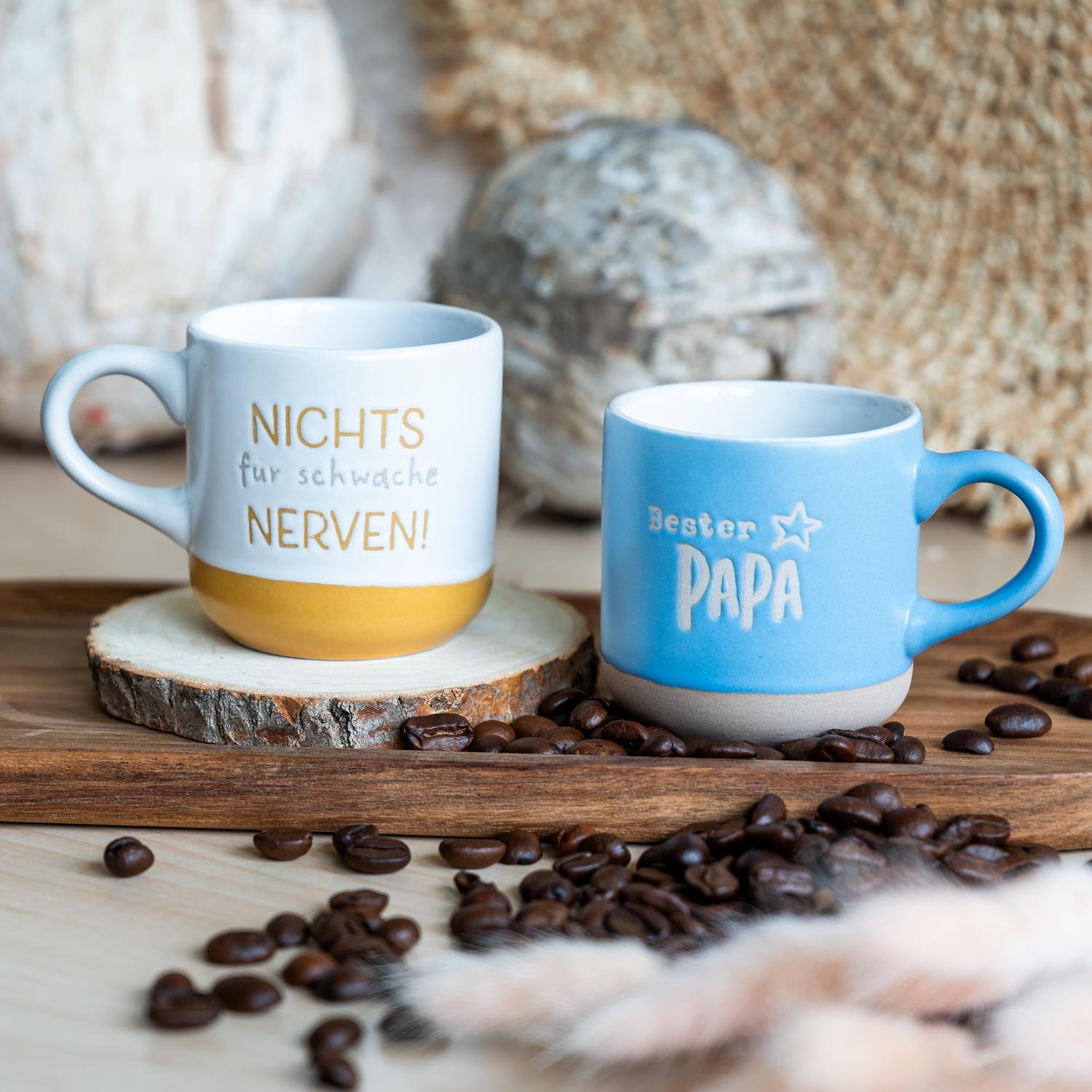 Zwei Espressotassen: blaue Tasse mit 'Bester Papa' und weiße Tasse mit gelbem Boden und Spruch
