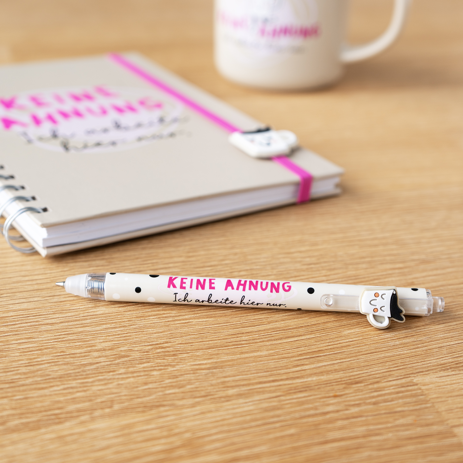 Weißer Gelstift mit pinkem Schriftzug »KEINE AHNUNG« und Punktemuster, liegt auf Holz