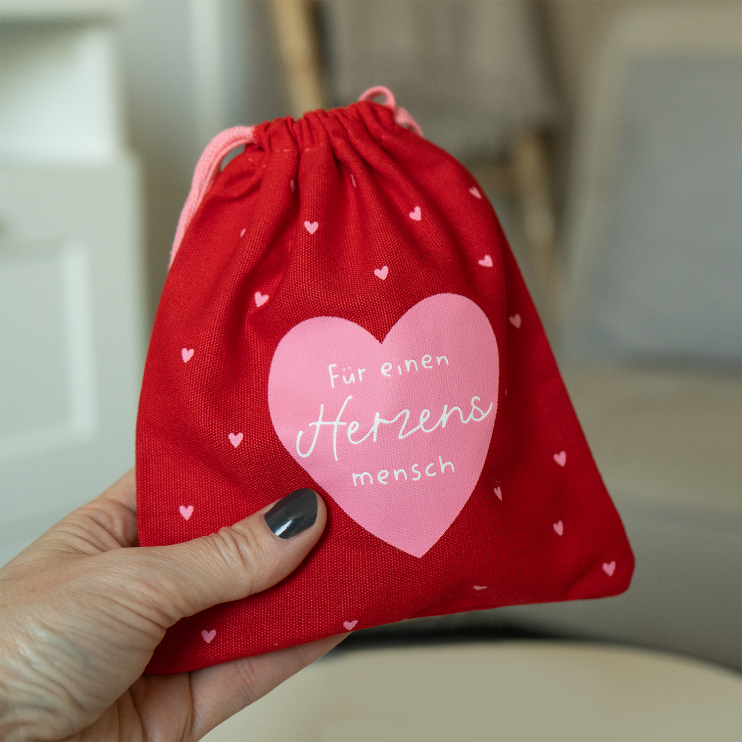 Rotes Geschenksäckchen aus Baumwolle mit rosa Herzmotiv und Schriftzug 'Für einen Herzen mensch', Zugband.