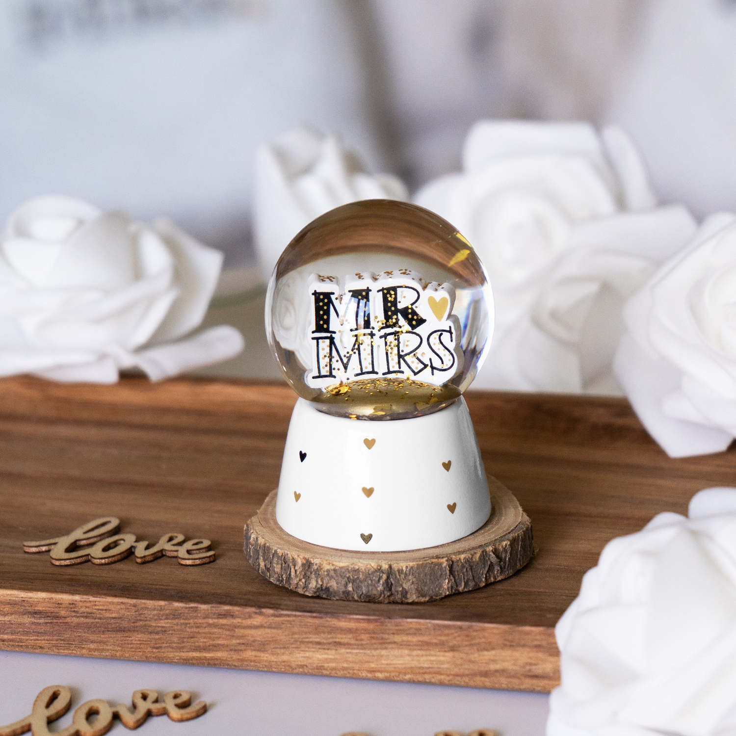 Transparente Schneekugel mit MR & MRS-Schriftzug, goldenen Herzen, auf weißem Sockel.