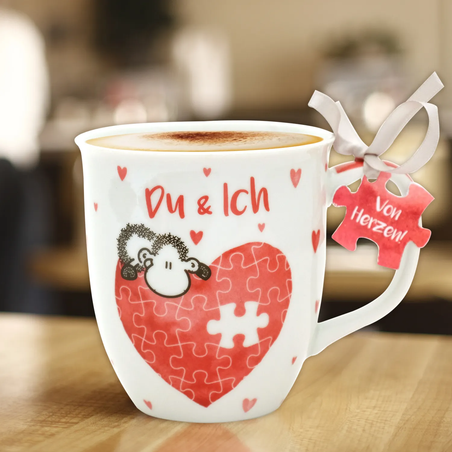 Weiße Porzellantasse mit rotem Herz-Puzzle-Motiv und Schäfchen, Du & Ich – ideal zum Jahrestag.