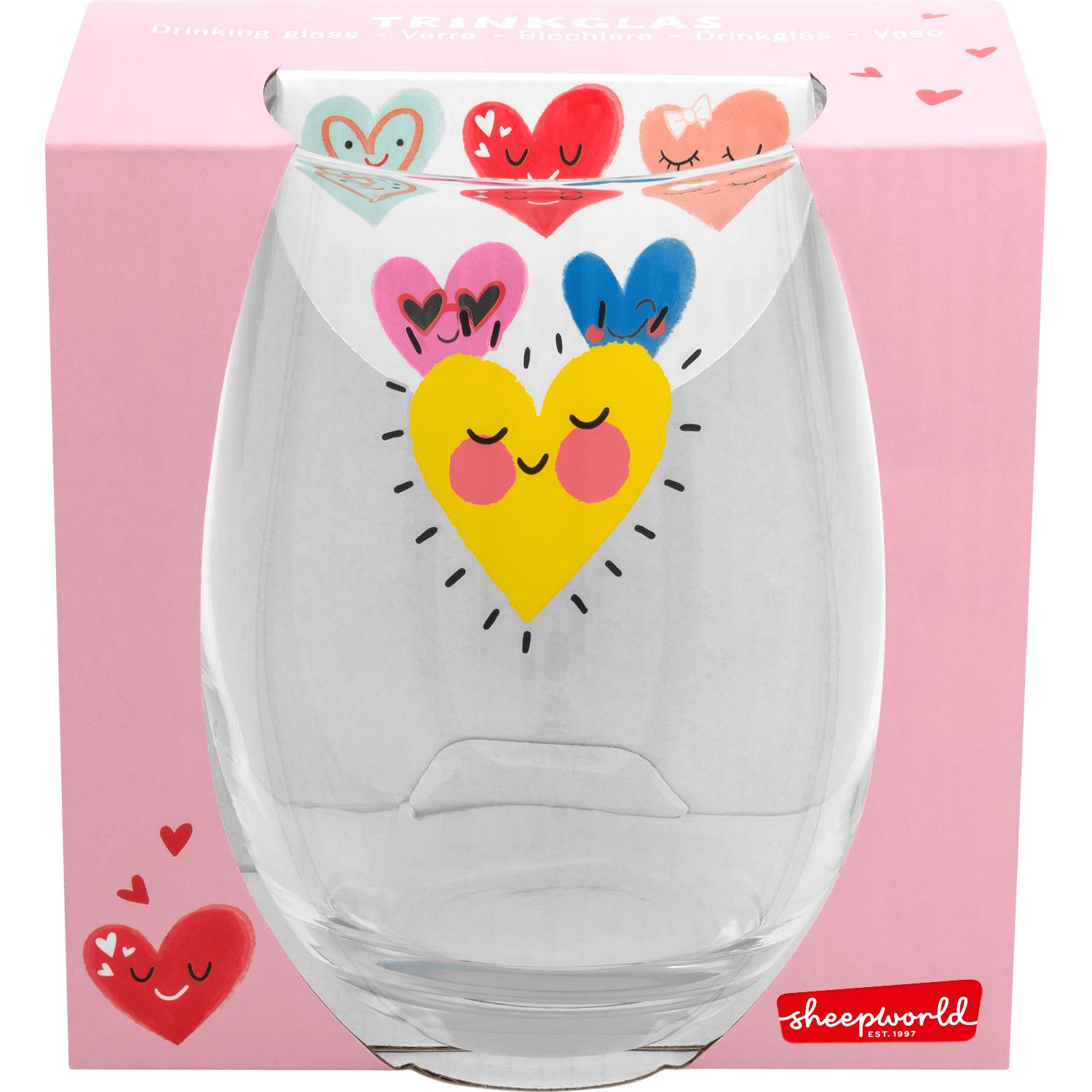 Trinkglas mit gelbem Herz-Motiv und bunten Herzen vor rosa Verpackung