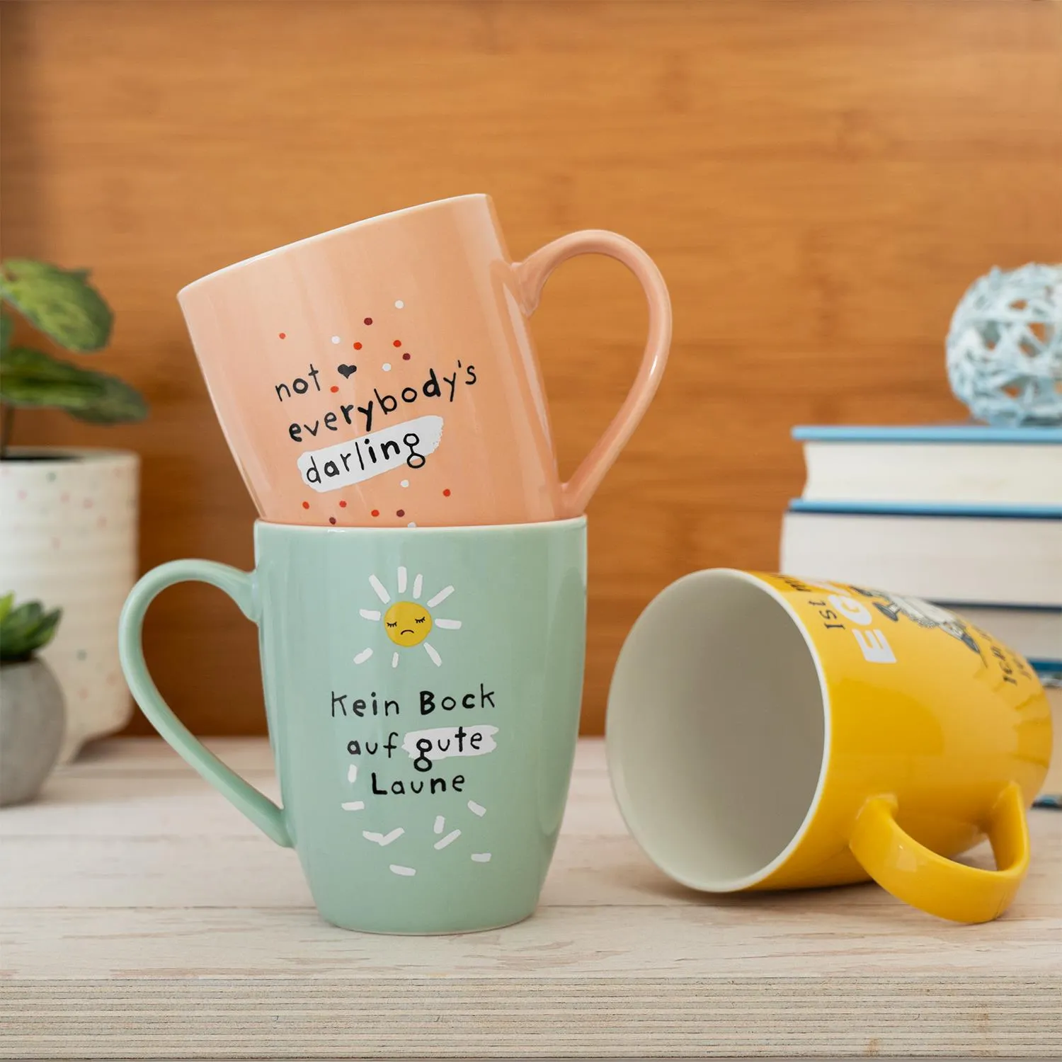 Pastellfarbene Becher mit Sprüchen: 'not everybody's darling' und 'Kein Bock auf gute Laune'.