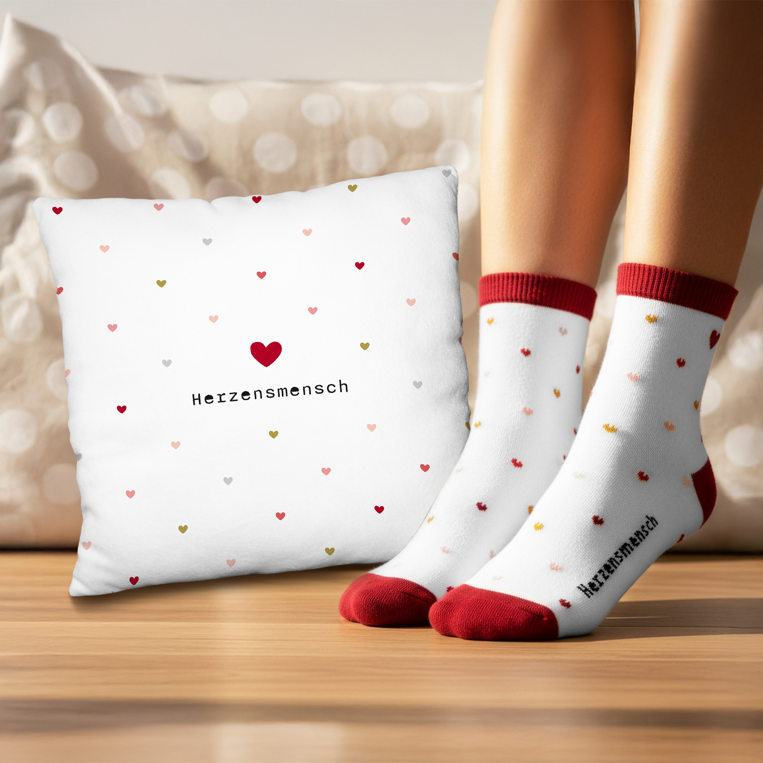 Weißes Kissen mit Herzchenmuster und rotem Herz, dazu passende weiße Socken mit kleinen Herzen.