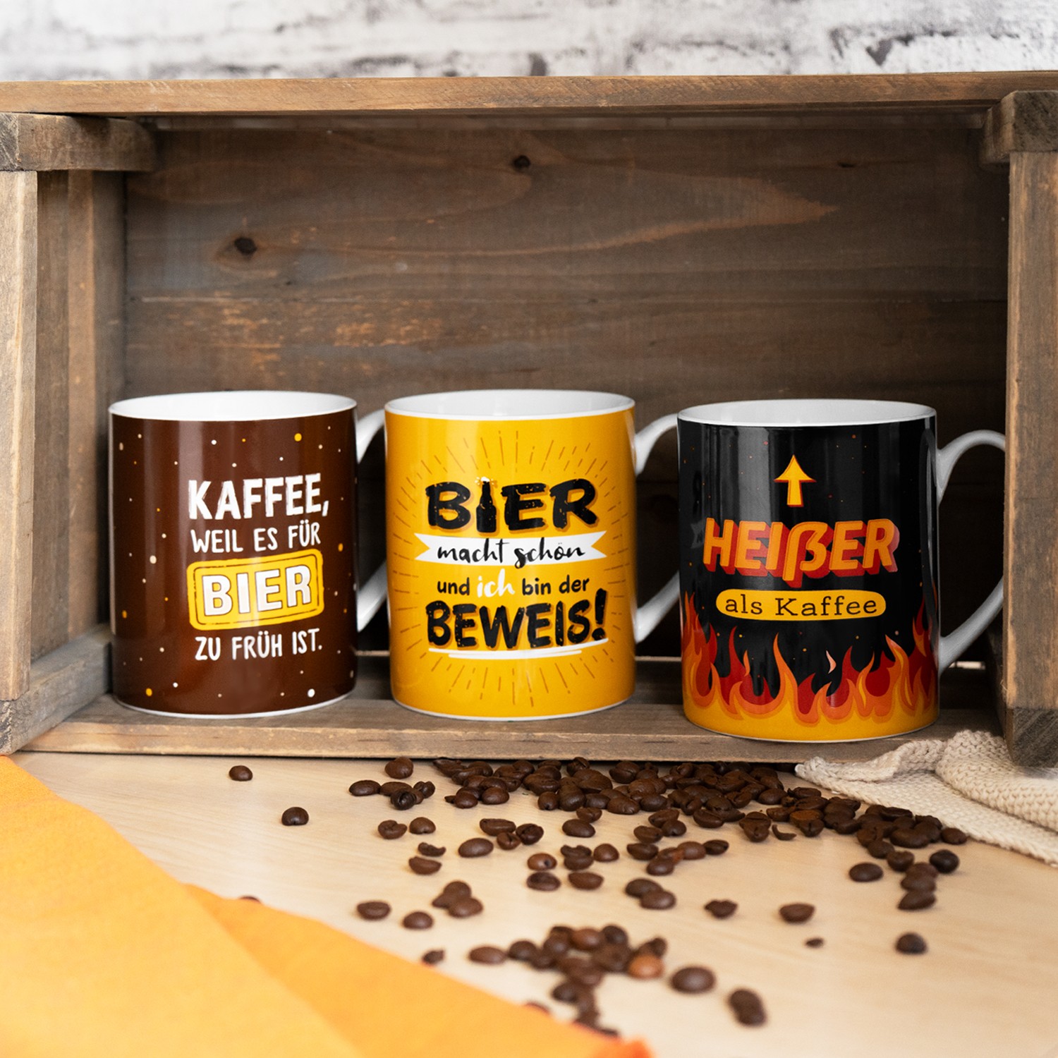 Drei XL-Tassen mit witzigen Sprüchen in Braun, Gelb und Schwarz auf Holz