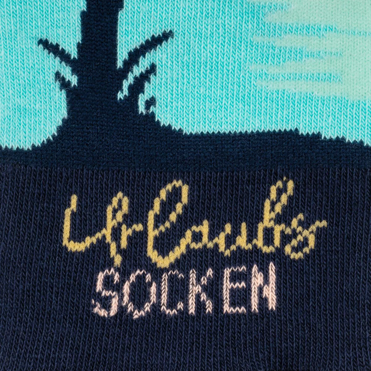 Zaubersocken Urlaub: gestrickte Socke mit Urlaubs-Motiv in Navy, Türkis und Rosa.