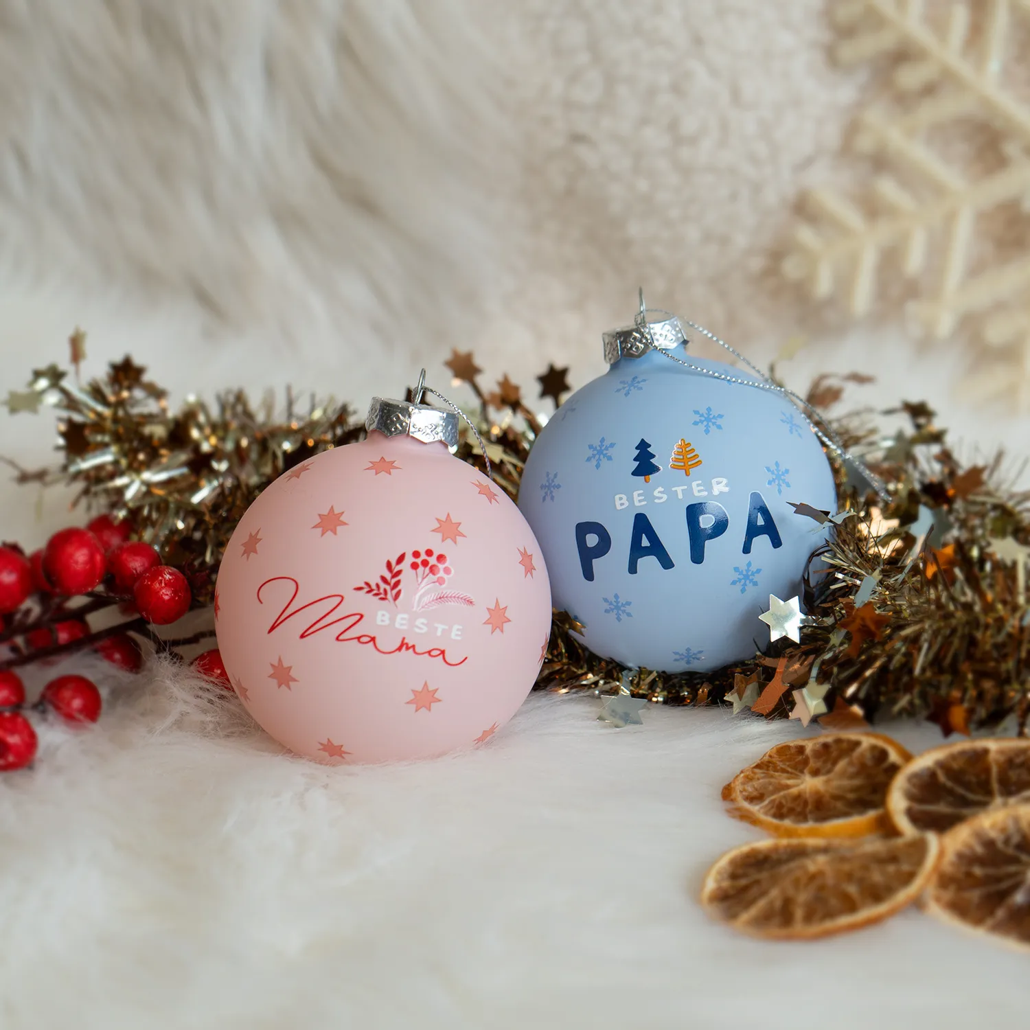Zwei pastellfarbene Glas-Weihnachtskugeln mit Schriftzügen 'Beste Mama' und 'Beste Papa'