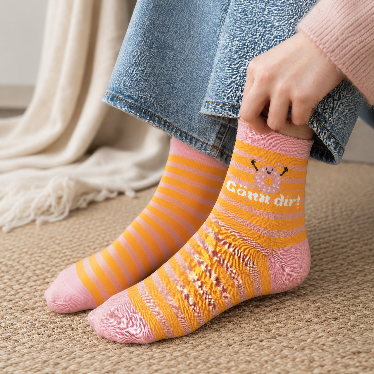 Pastellrosa Socken mit orange-gelben Streifen und Schäfchen-Motiv, Spruch 'Gönn Dir!'.