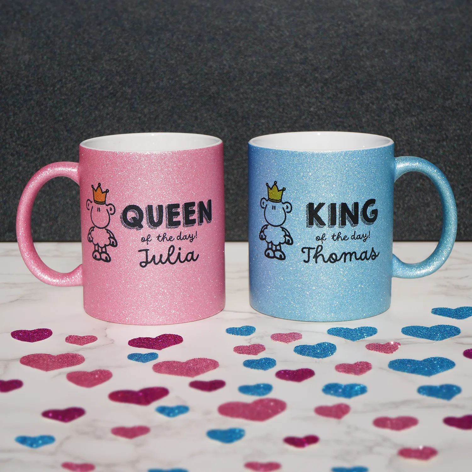 Zwei glitzernde Porzellantassen pink und blau mit Kronen-Schaf-Motiv und Namen