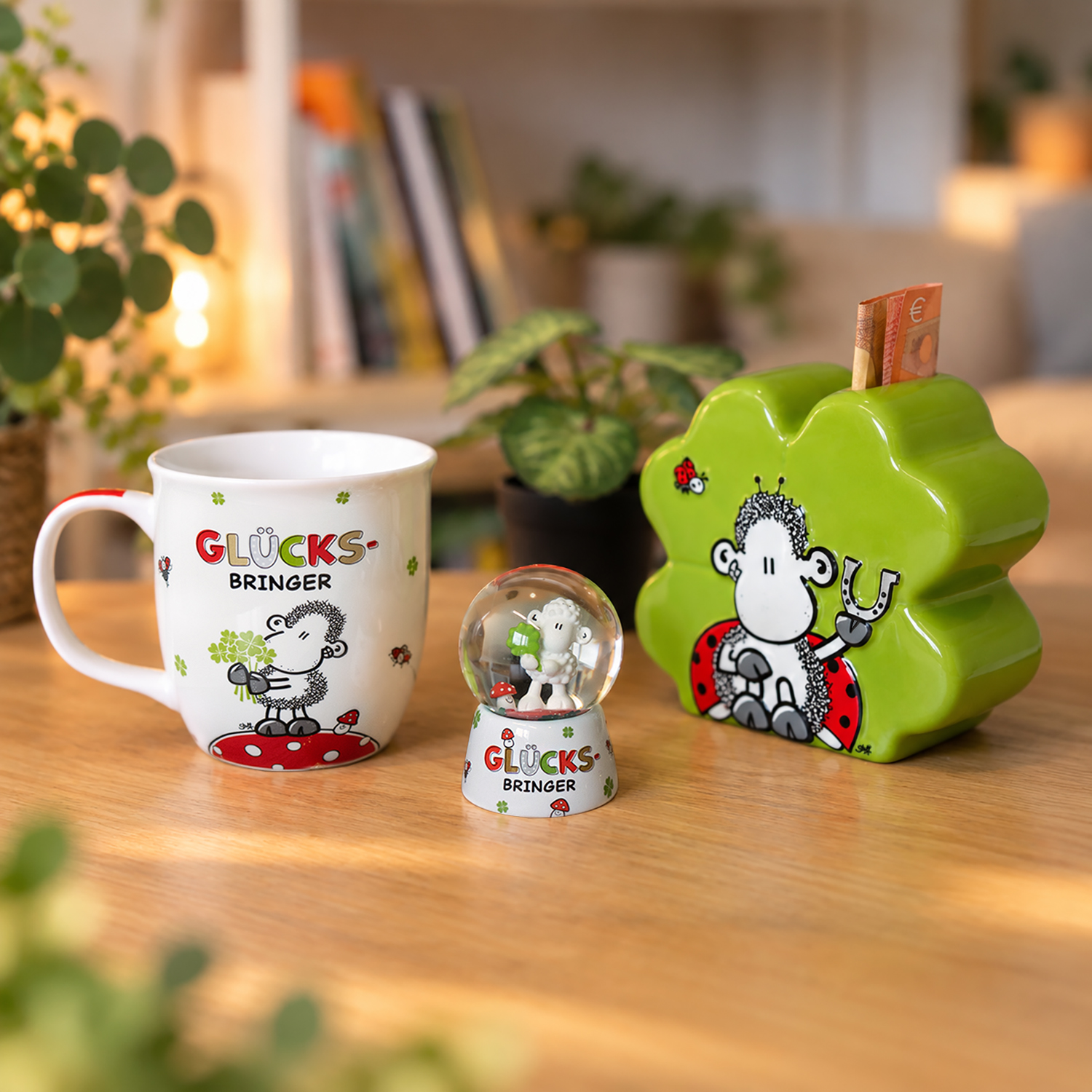 Weißer Porzellan-Becher mit Schaf-Motiv, mintgrüne Kleeblattform-Spardose und Schneekugel mit Schäfchen – Glücksbringer-Set