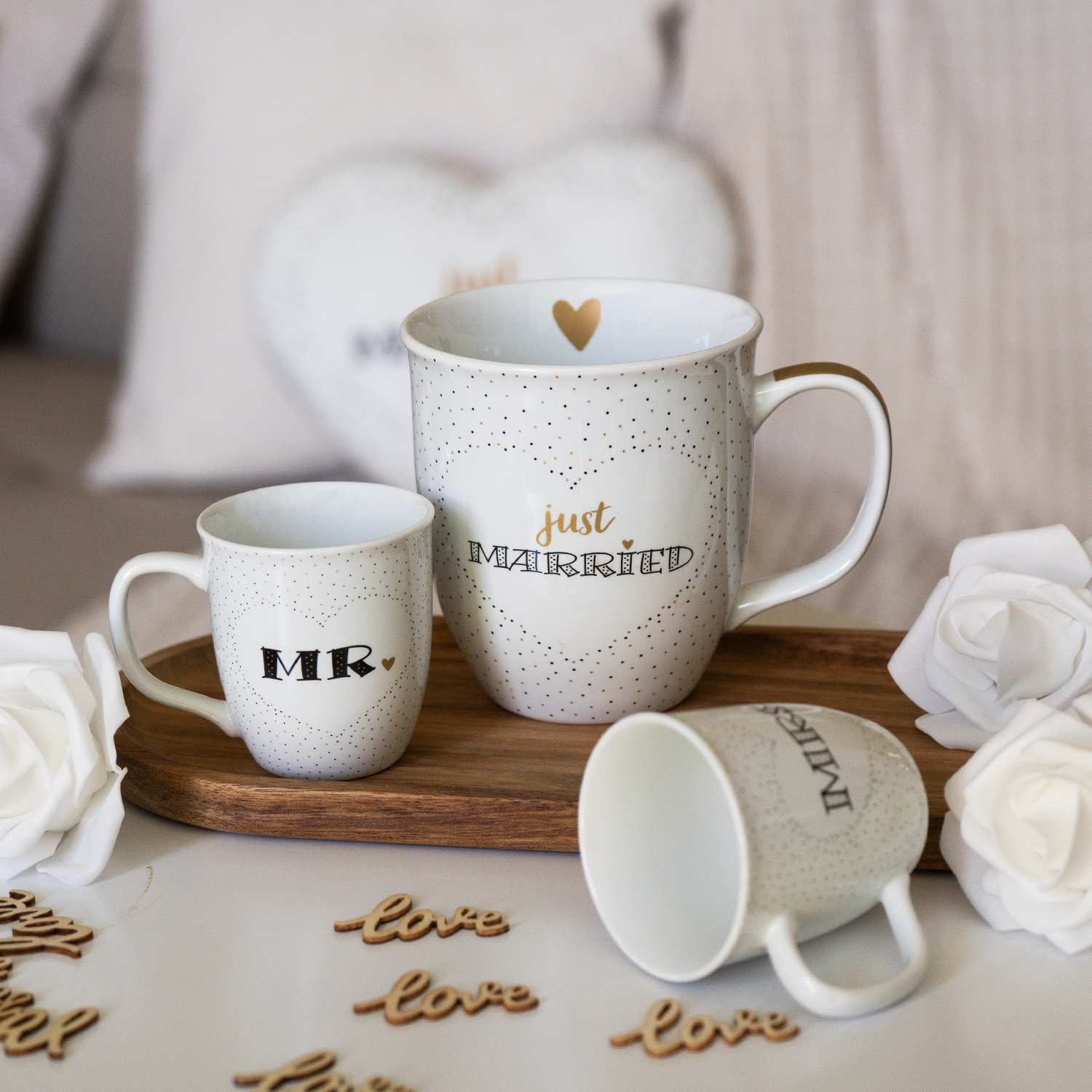Weiße Porzellan-Tassen mit goldenen Herzen und dem Schriftzug 'Just Married' auf gepunkteter Oberfläche