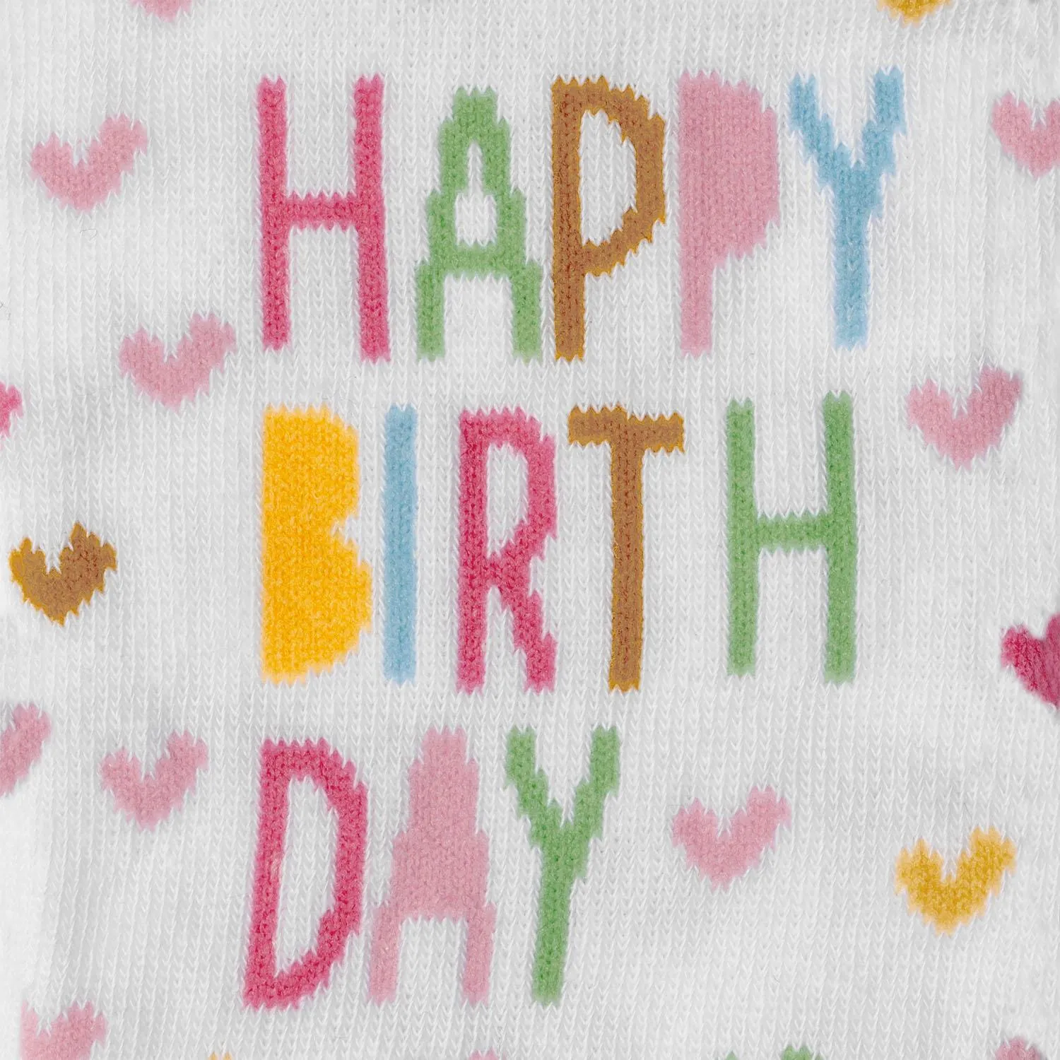 Zaubersocken Happy Birthday – bunter Schriftzug auf weißem Strick mit Herzchen.