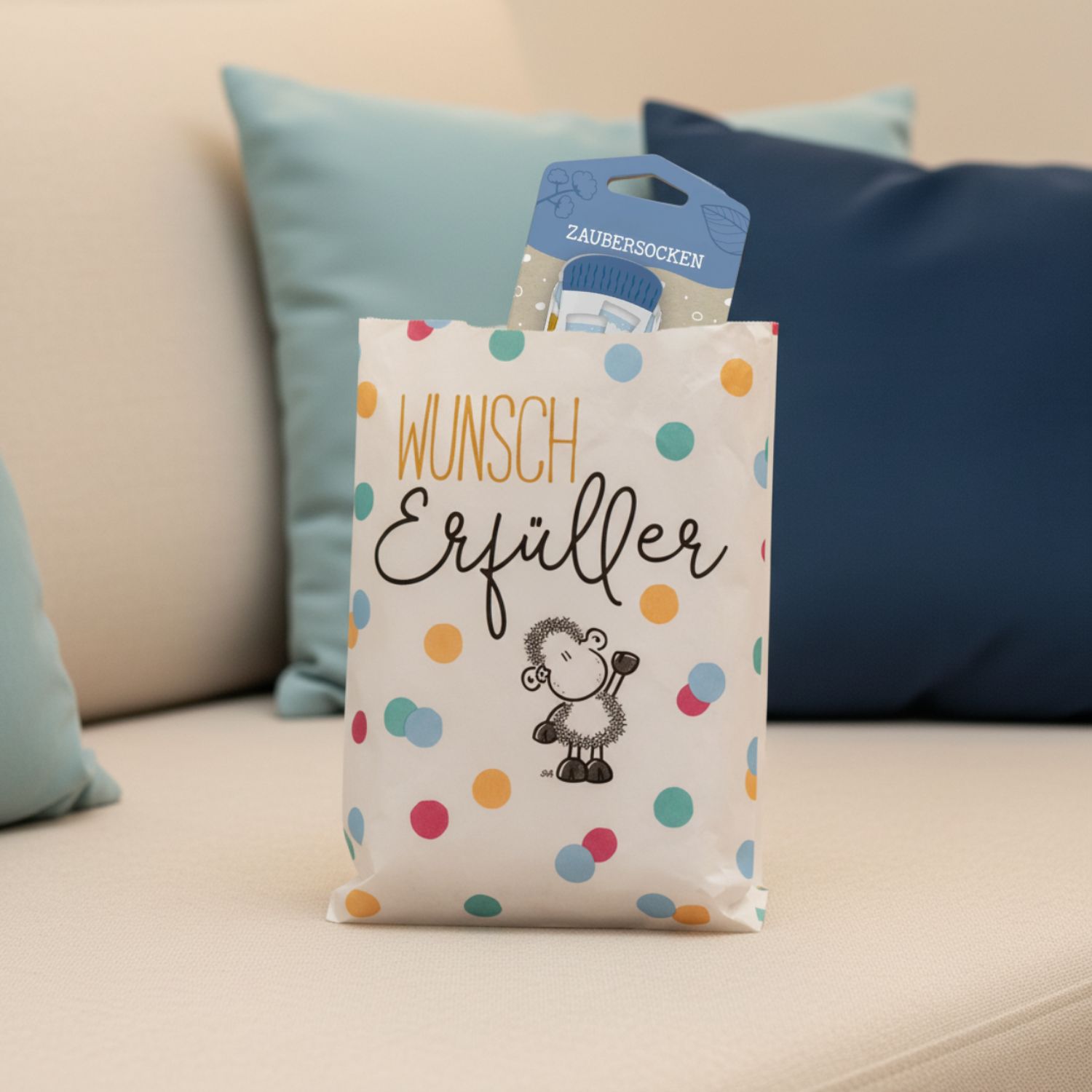 Weiße Geschenktüte mit Schäfchen-Motiv und bunten Punkten, vier Zaubersocken versteckt.