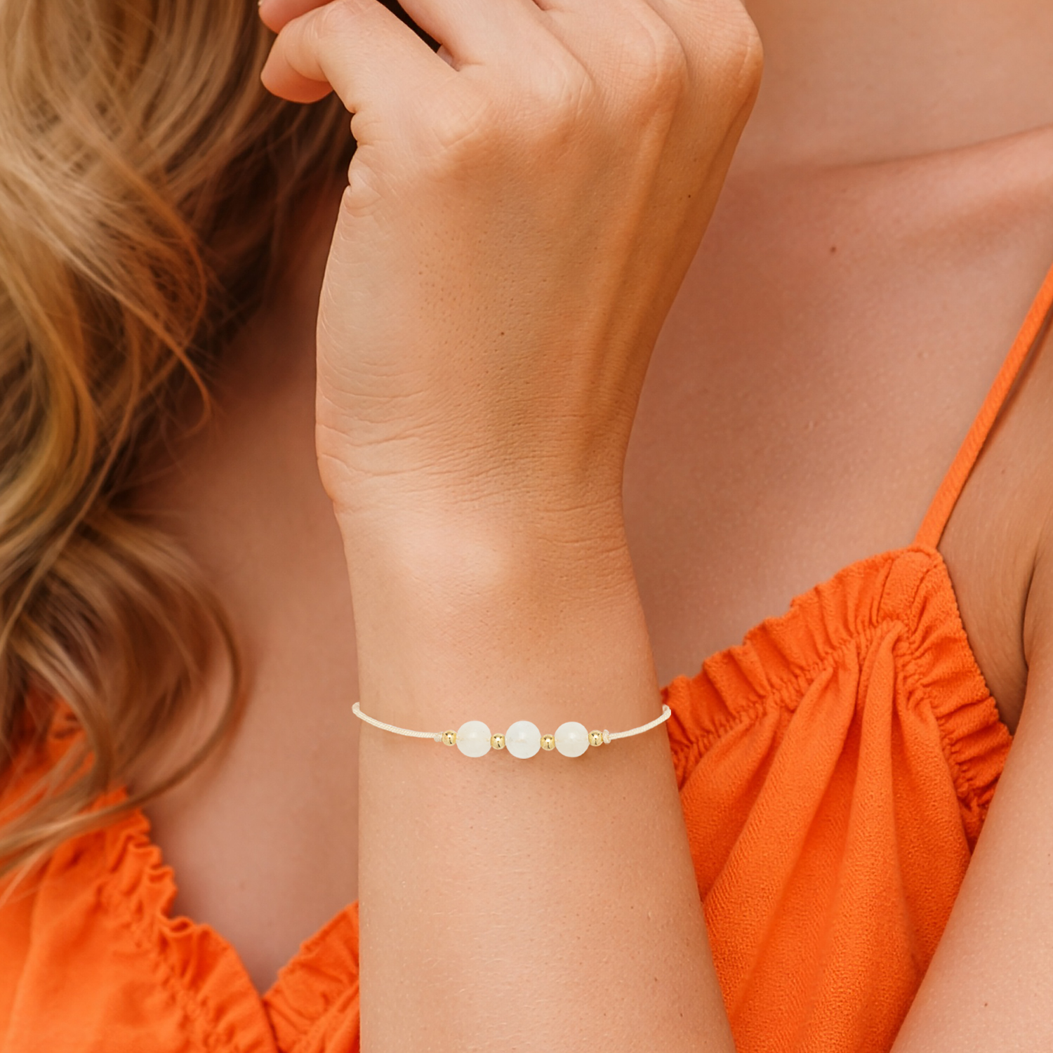 Zartes Armband mit drei weißen Perlen auf cremefarbener Schnur