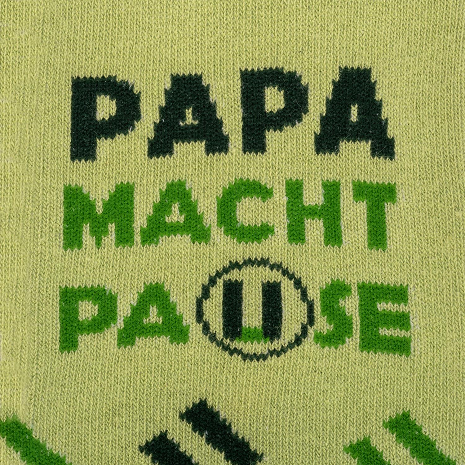 Grüne Socken mit dunklem Schriftzug 'PAPA MAGIC' in gestricktem Muster