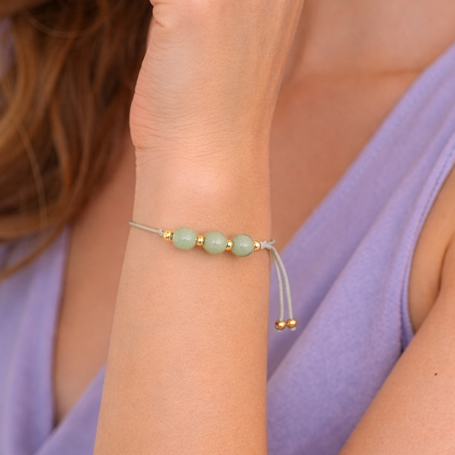 Armband mit drei mintgrünen Aventurin-Perlen und goldenen Zwischenperlen auf grauem Faden