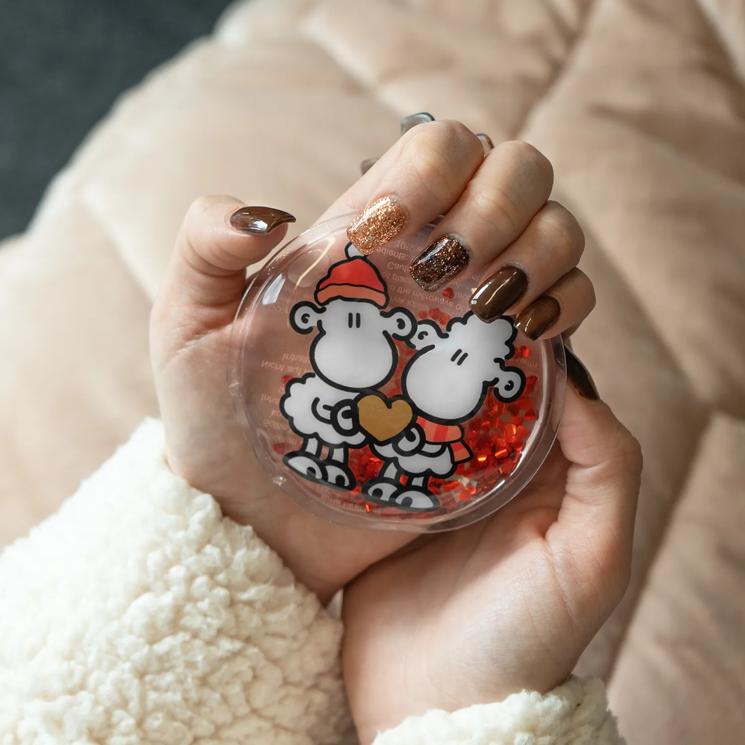 Runder Handwärmer in klarem Behälter mit zwei Schäfchen und rotem Herz.