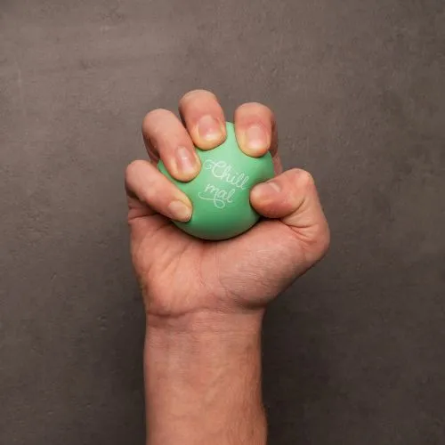 Mintgrüner Knautschball mit der Aufschrift "Chill mal", in der Hand eines Menschen.