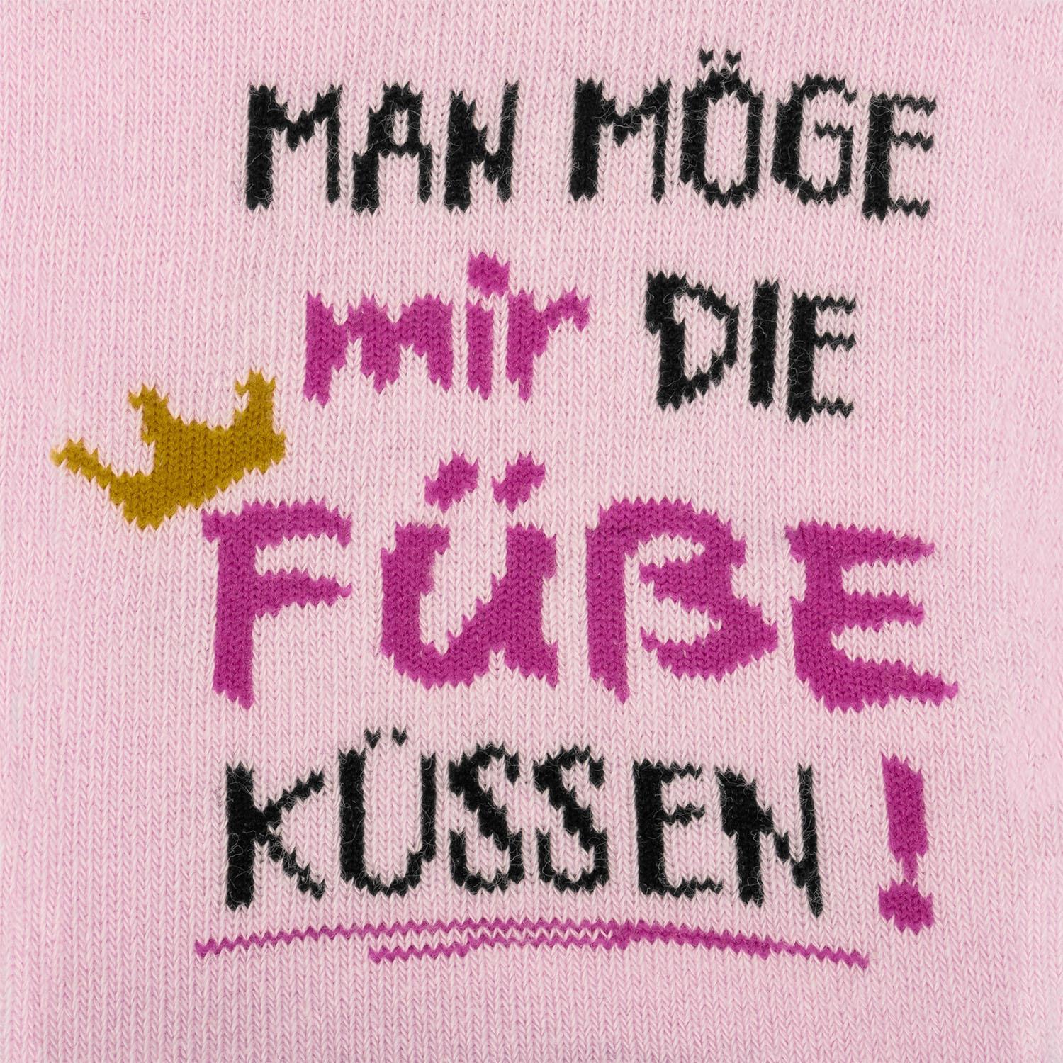 Pink gestrickte Socke mit frechem Spruch 'Man möge Füße küssen' und Krönchen.