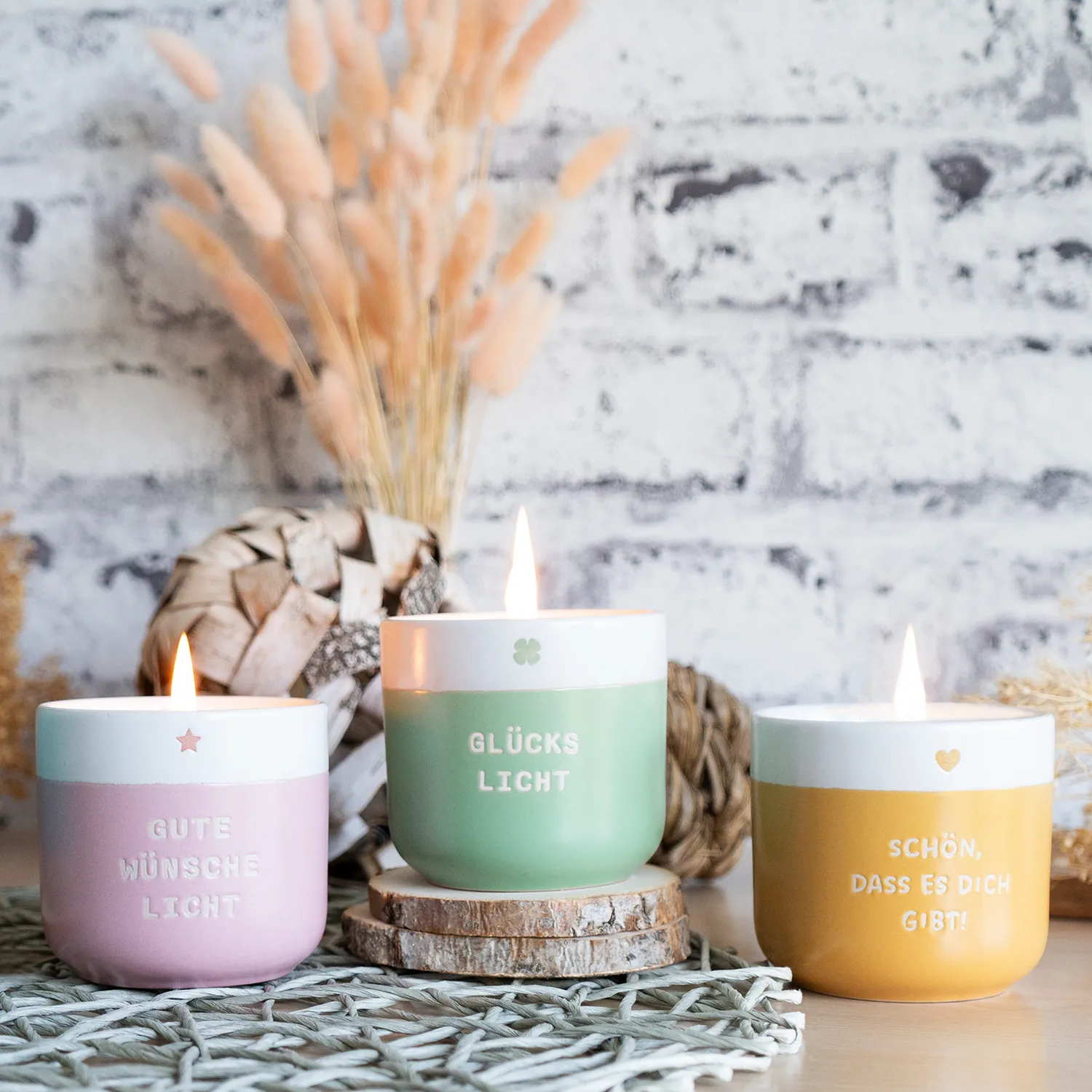 Drei pastelfarbene Knisterkerzen aus Steinzeug mit Schriftzüge.