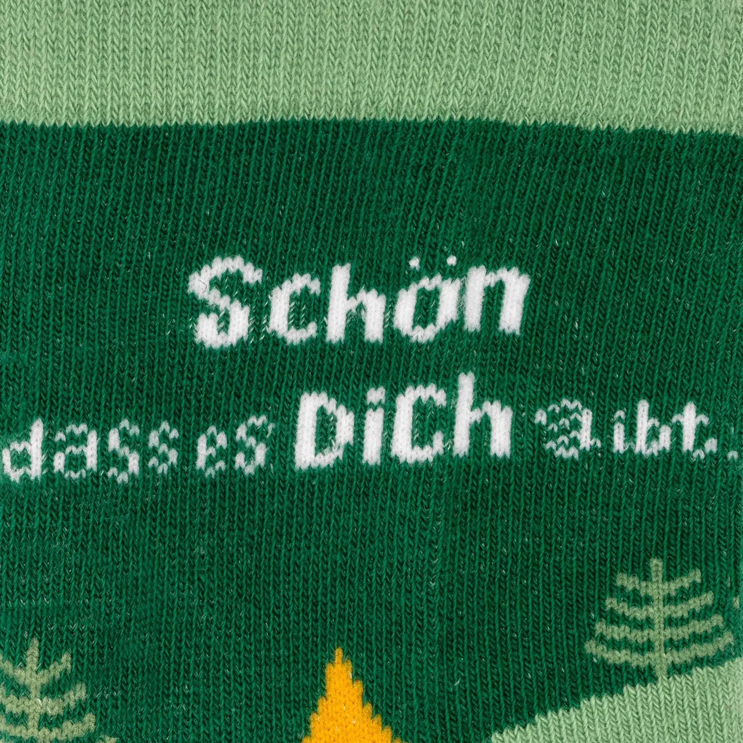 Grüne Stricksocke mit weißem Schriftzug 'Schön, dass es Dich gibt!'