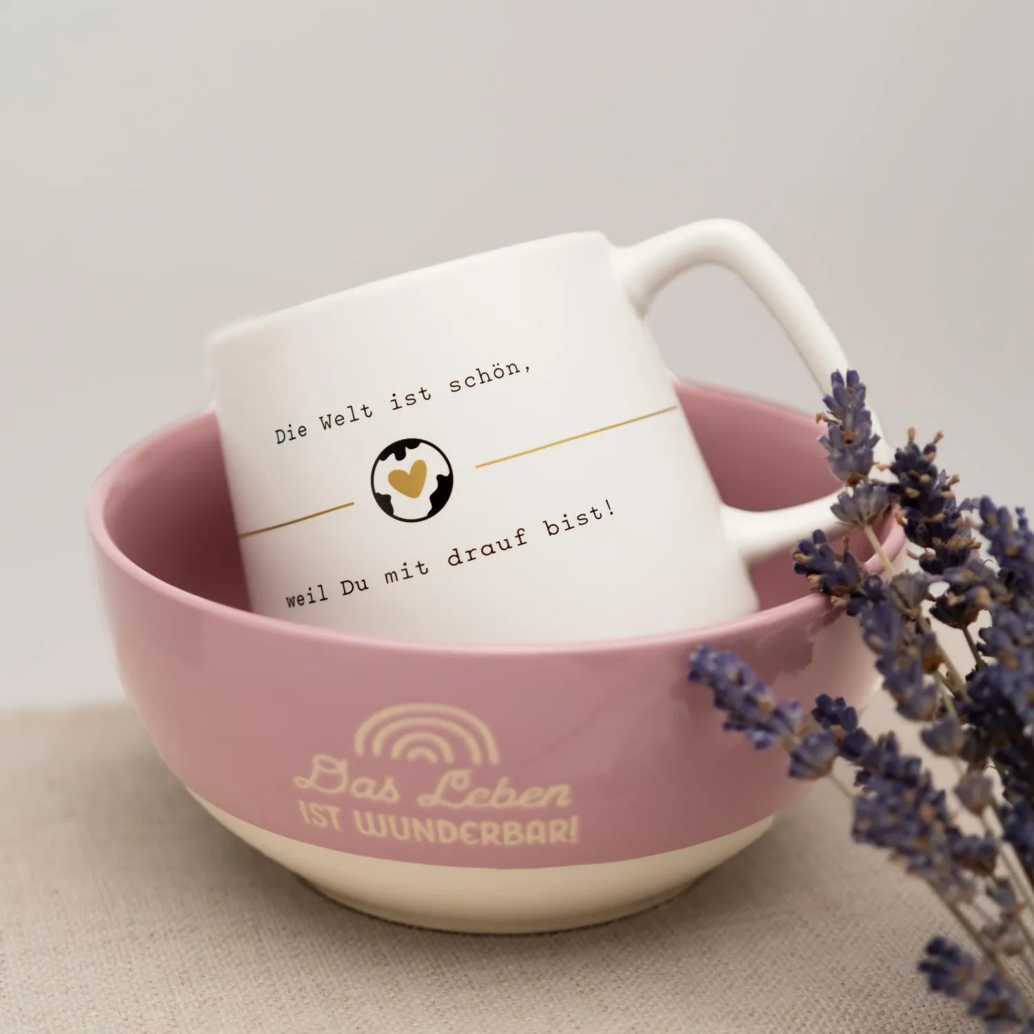 Weiße konische Steinzeug-Tasse mit rosa Band und Gold-Druck, Spruch 'Die Welt ist schön, weil Du mit drauf bist!'