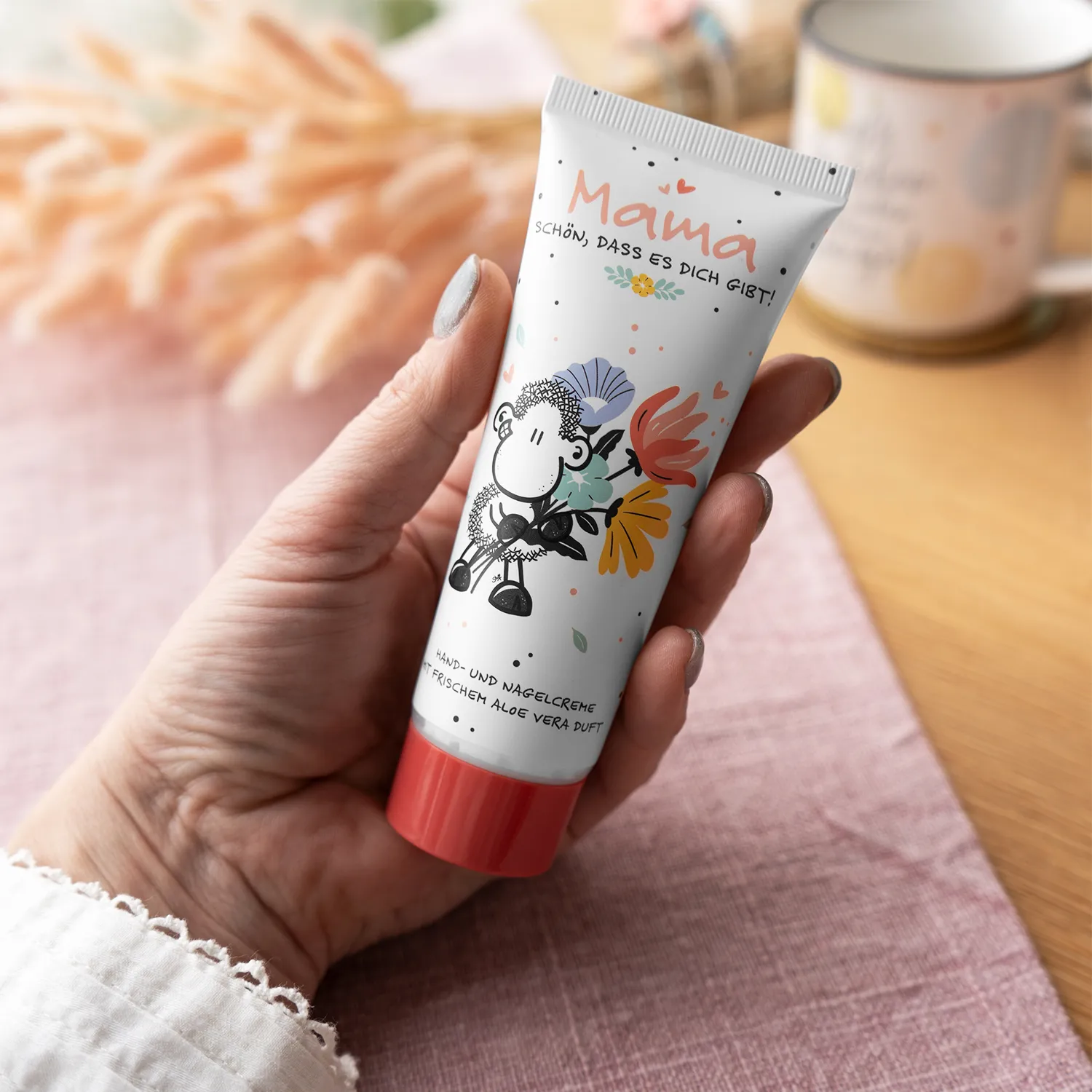 Weiße Tube Hand- und Nagelcreme mit roter Kappe und Schäfchen-Motiv