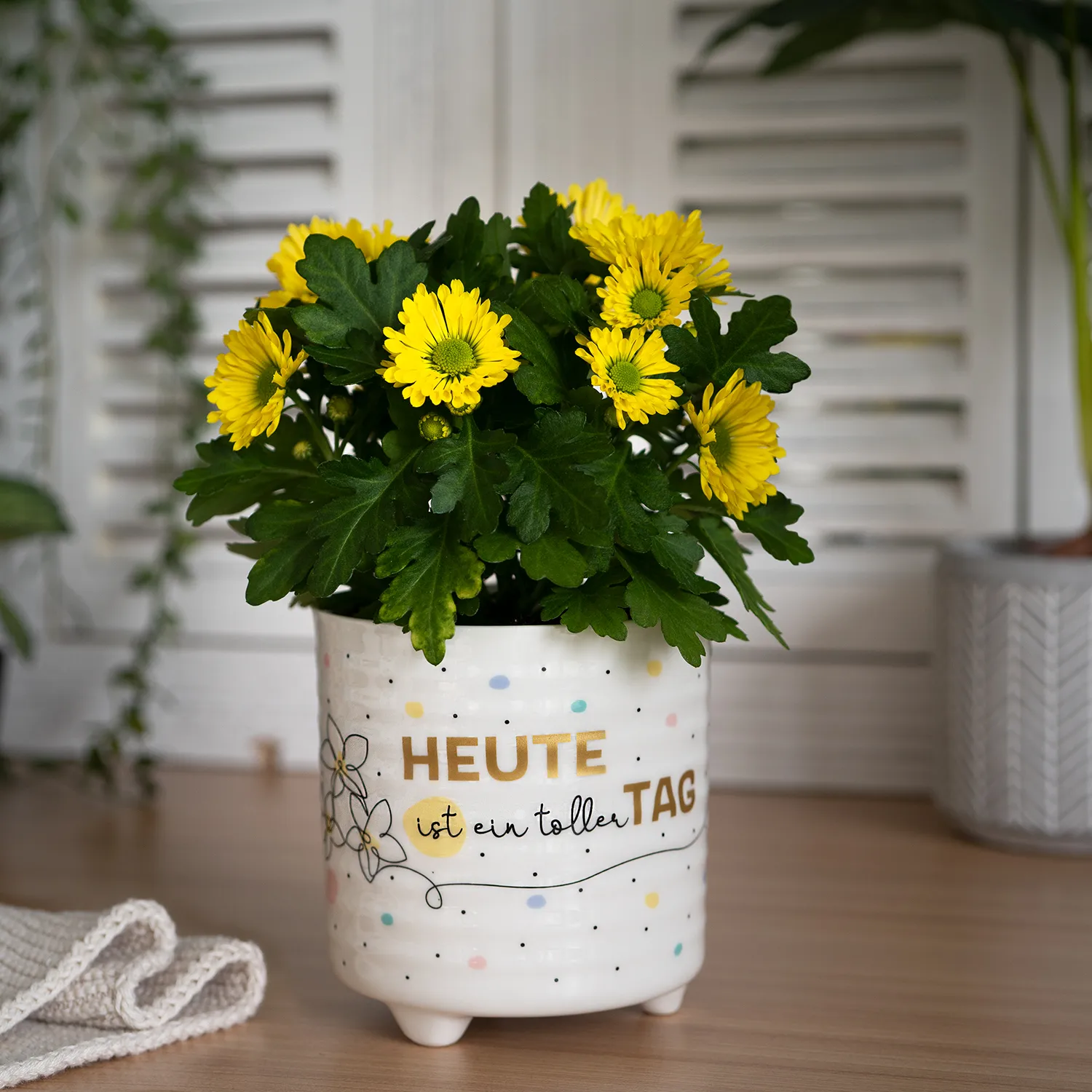 Weißer Porzellan-Übertopf mit gelben Blumen und Spruchdruck