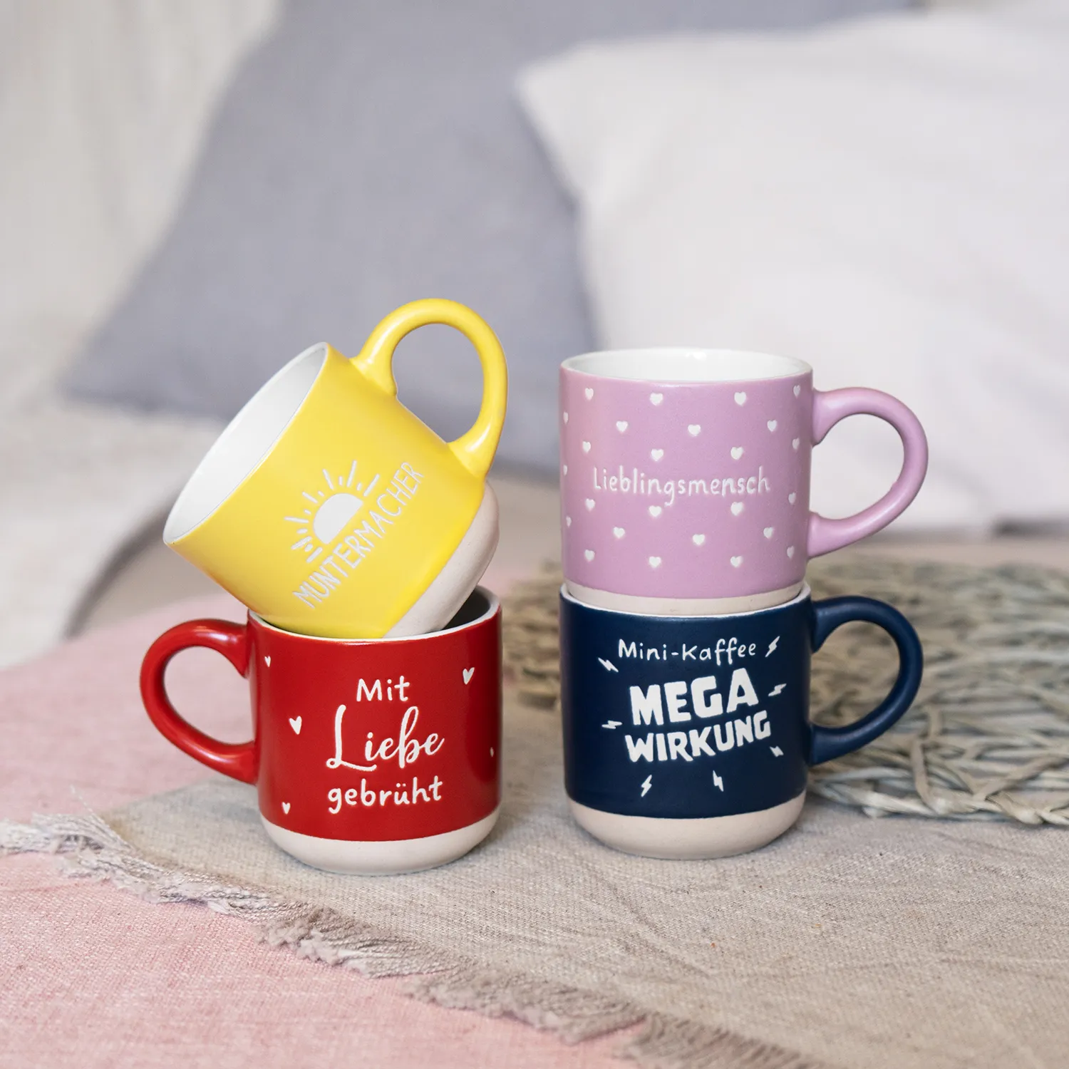 Vier bunte Espressotassen in Gelb, Rot, Pink und Navy mit Sprüchen wie Lieblingsmensch und Mega Wirkung