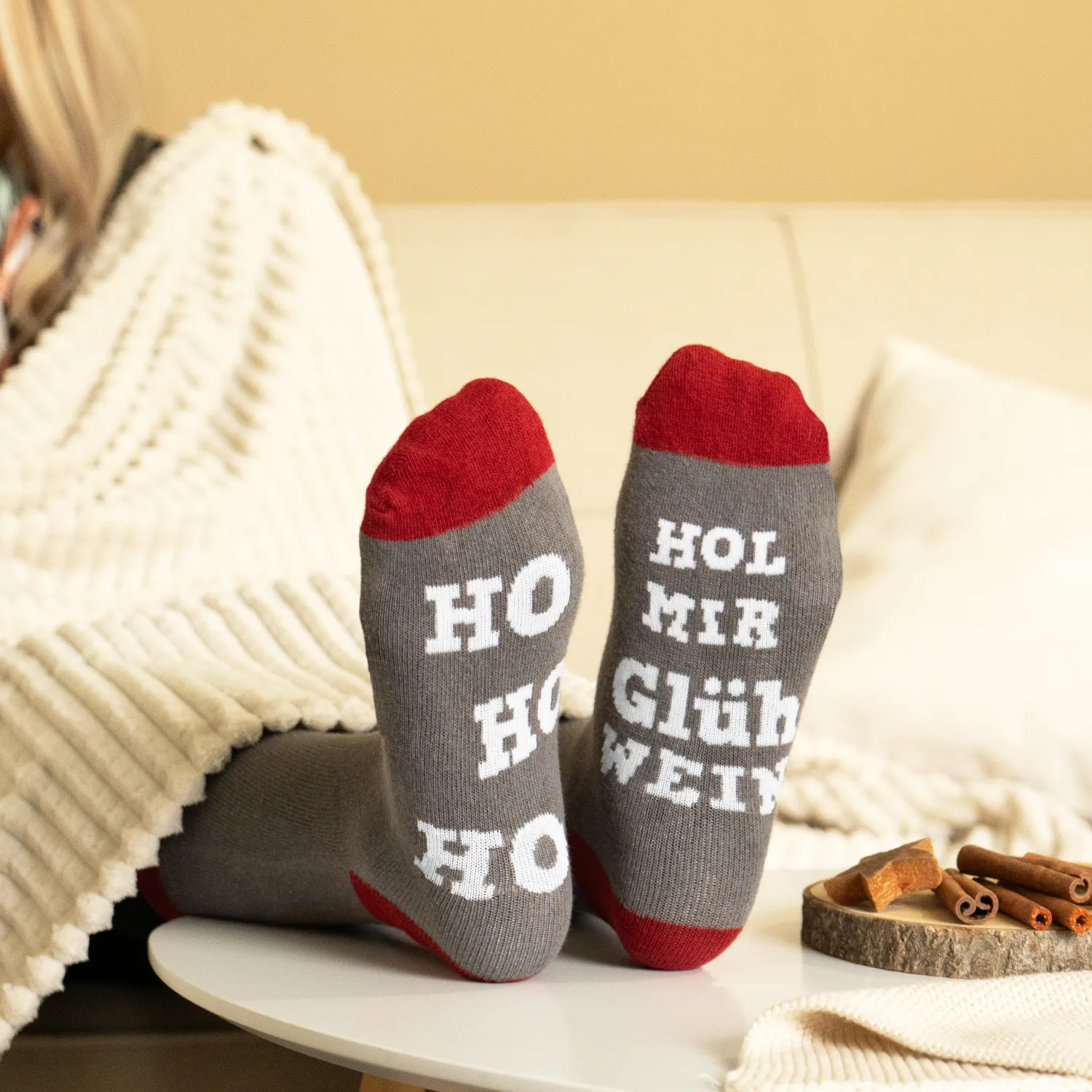 Paar graue Socken mit roten Zehen und Fersen, weiße Schrift HO HO HO GLÜHWEIN