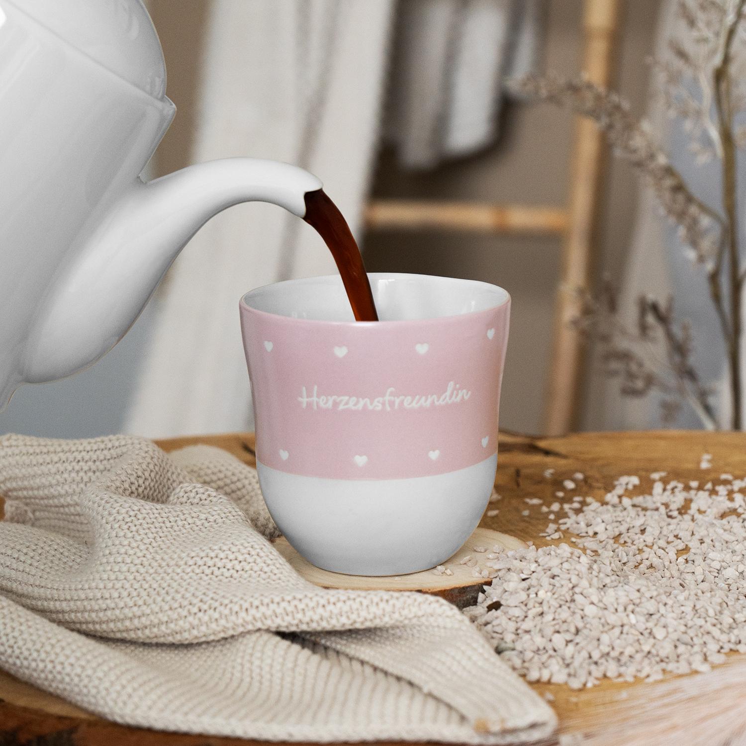 Rosa Keramikbecher mit weißem Boden, Herzchen und der Aufschrift 'Herzensfreundin', wird mit Tee gefüllt.