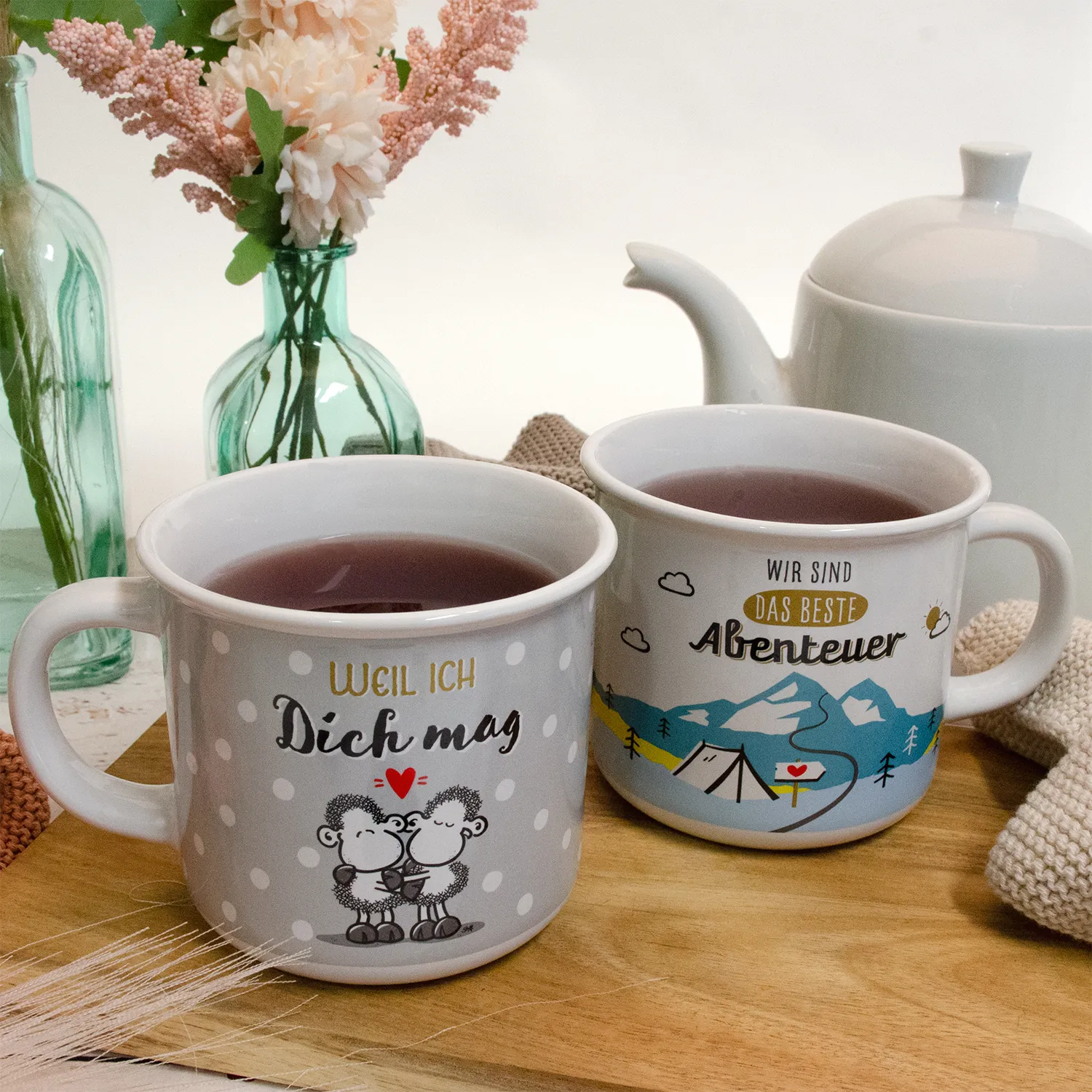 Zwei Keramik-Becher mit Schäfchen-Motiv und Liebesbotschaften auf Holztablett