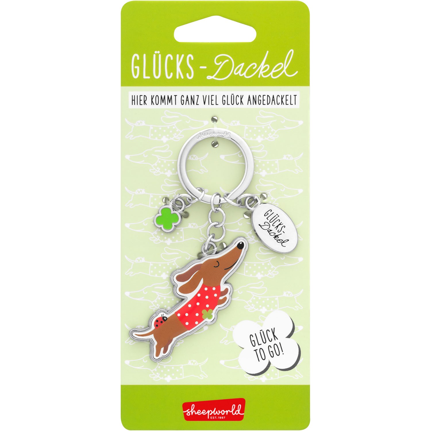 Schlüsselanhänger Glücks-Dackel mit silbernem Ring, rotem Kleid und Kleeblatt-Charm.