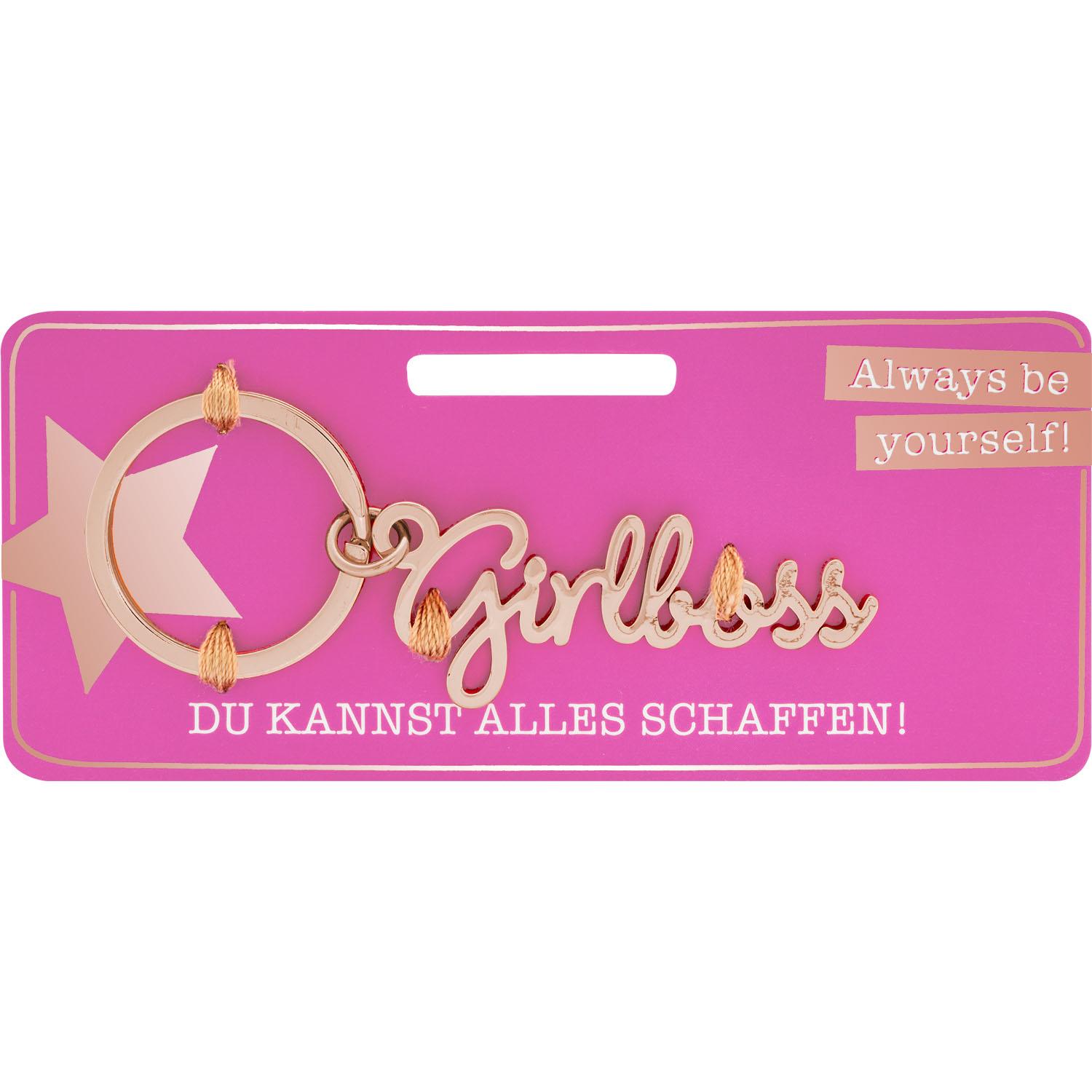 Roségoldfarbener Schlüsselanhänger mit Schriftzug Girlboss vor pinkem Verpackungshintergrund.