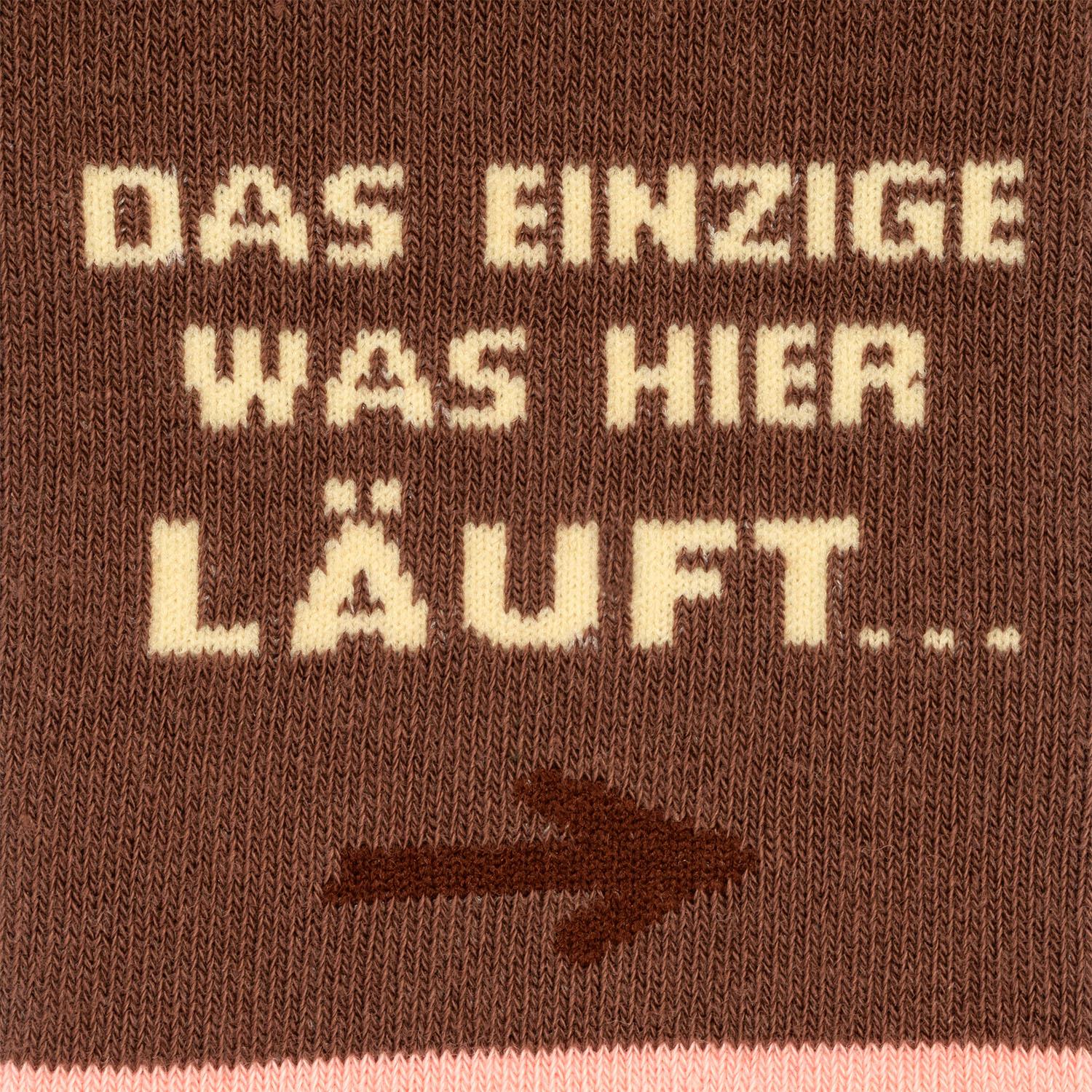 Braune Zaubersocken mit cremefarbener Aufschrift 'DAS EINZIGE WAS HIER LÄUFT' und Pfeil