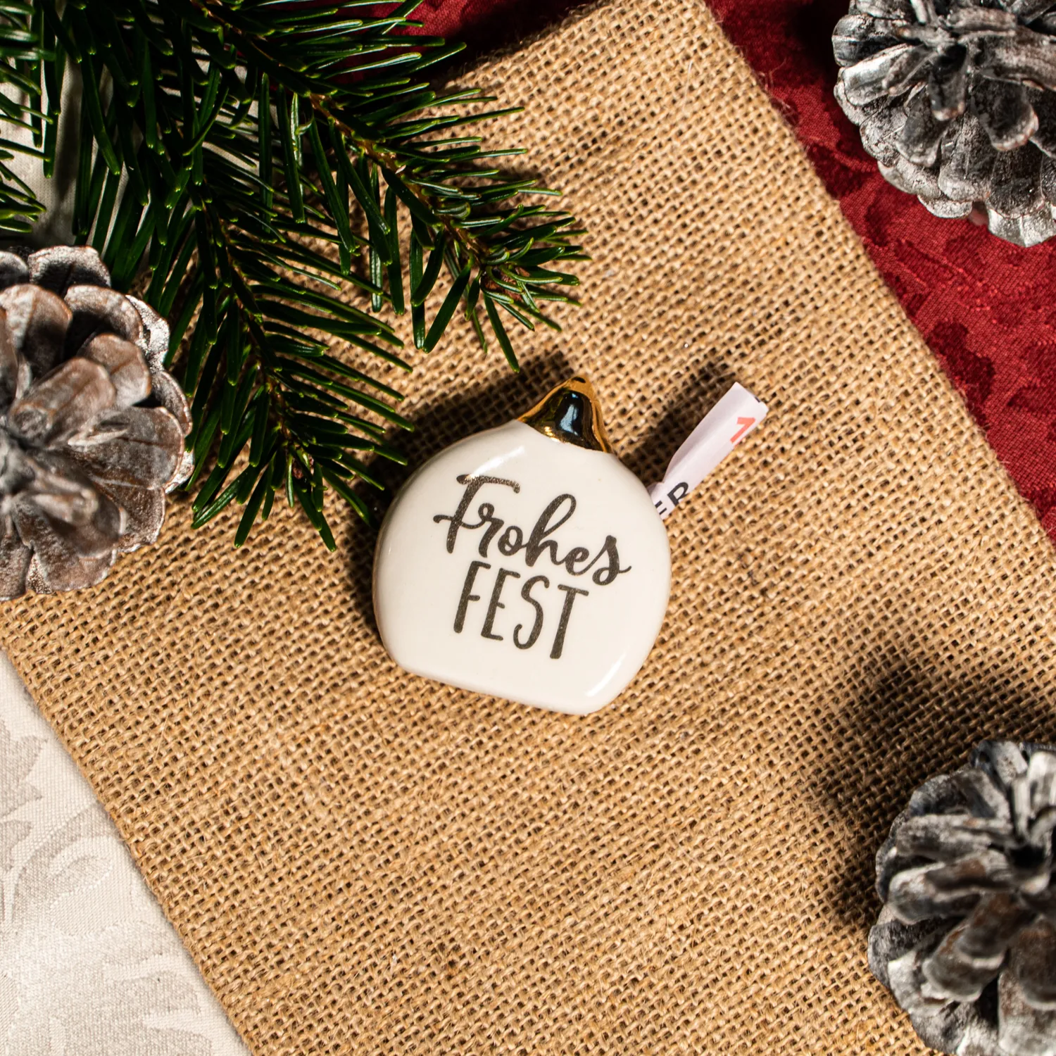 Weißer Porzellan-Christbaumkugel-Anhänger mit Goldakzent und Schriftzug 'Frohes Fest'