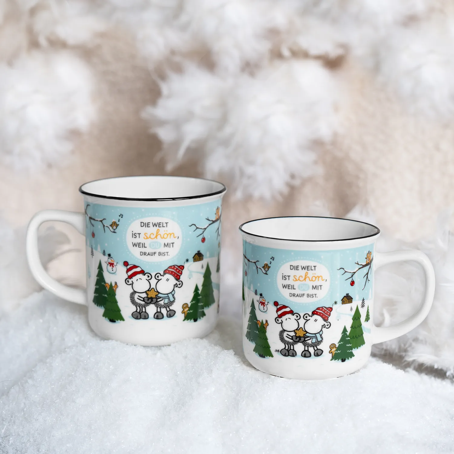 Weiße Porzellan-Becher mit winterlichem Motiv: zwei Schafe in Mützen vor Tannen auf blauem Hintergrund.
