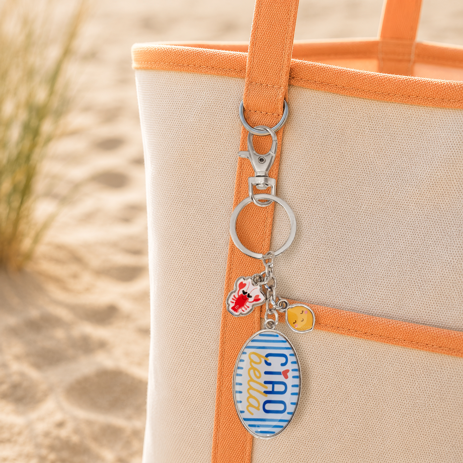 Taschenanhänger CIAO bella mit Charm-Anhänger am orangefarbenen Strap