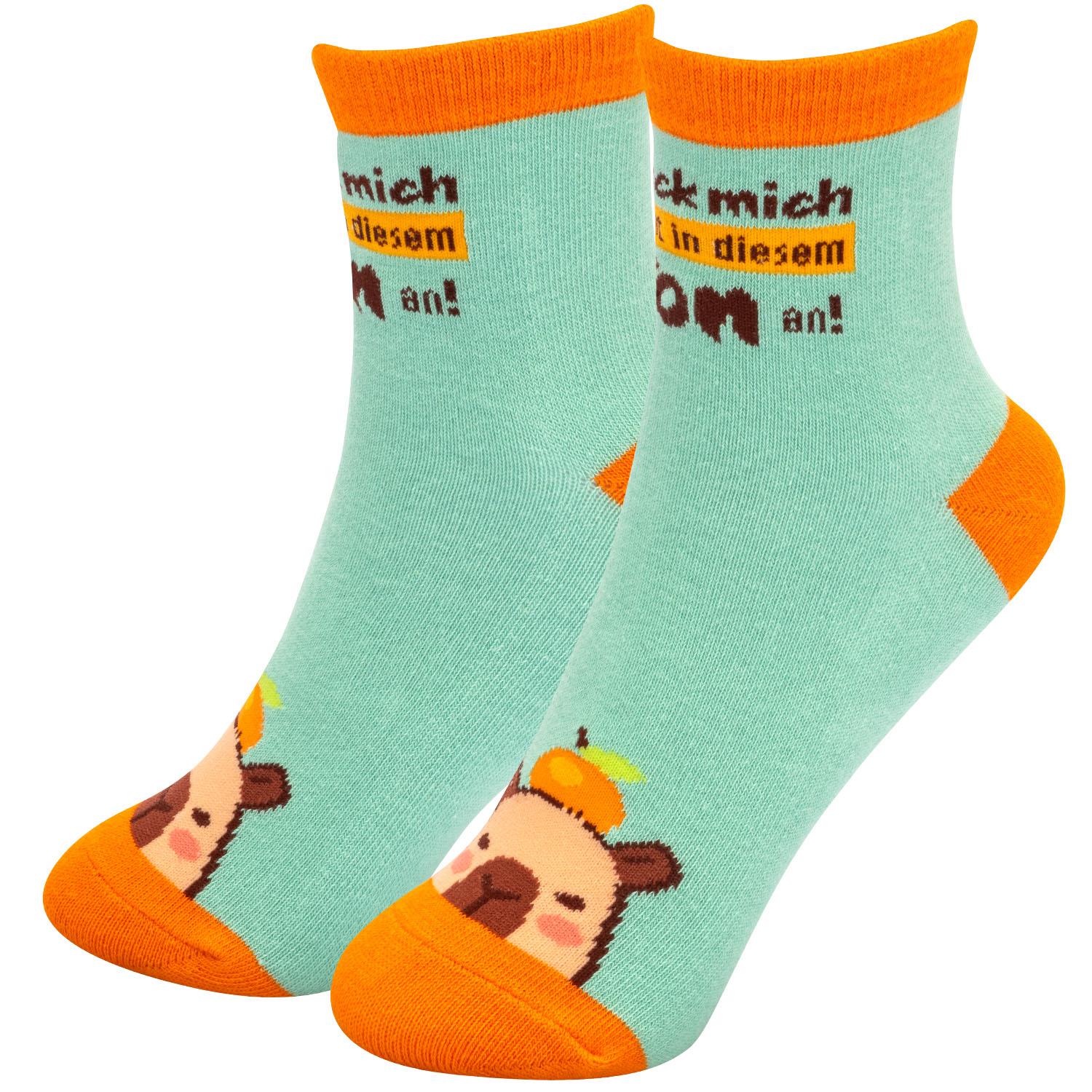 Mintgrüne Zaubersocken mit orangefarbenen Spitzen und Bären-Motiv; Spruch 'nicht in diesem Ton' auf gelbem Hintergrund