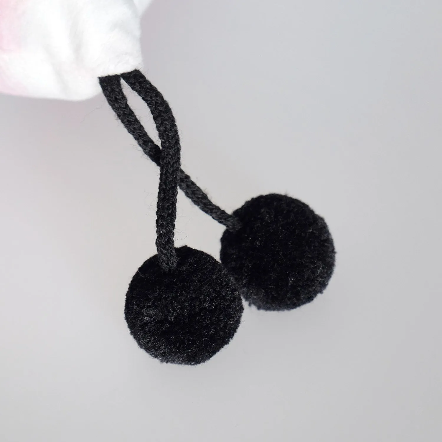 Zwei schwarze Plüschpompons an einer Schnur – kuschelige Deko