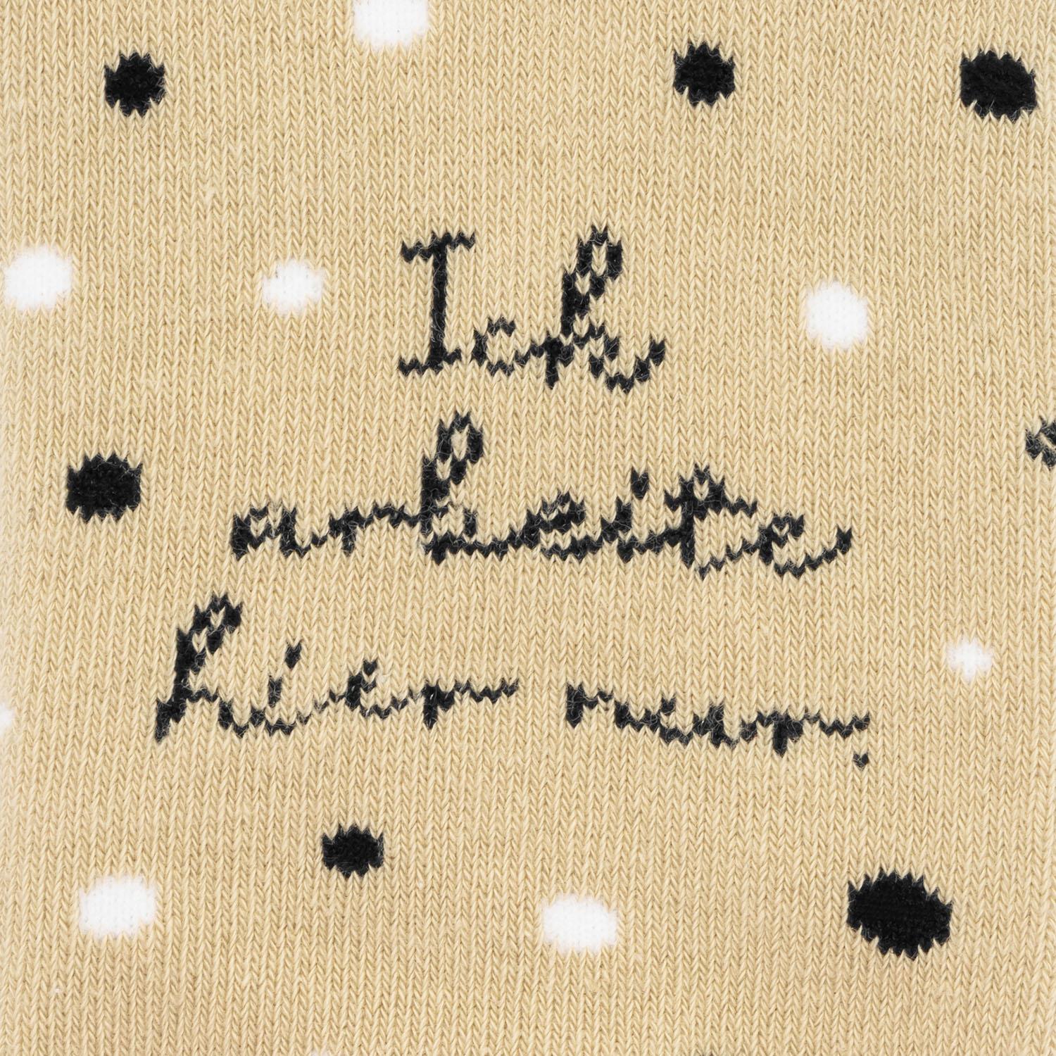 Beigefarbene Socke mit schwarzen Tupfen und Schriftzug