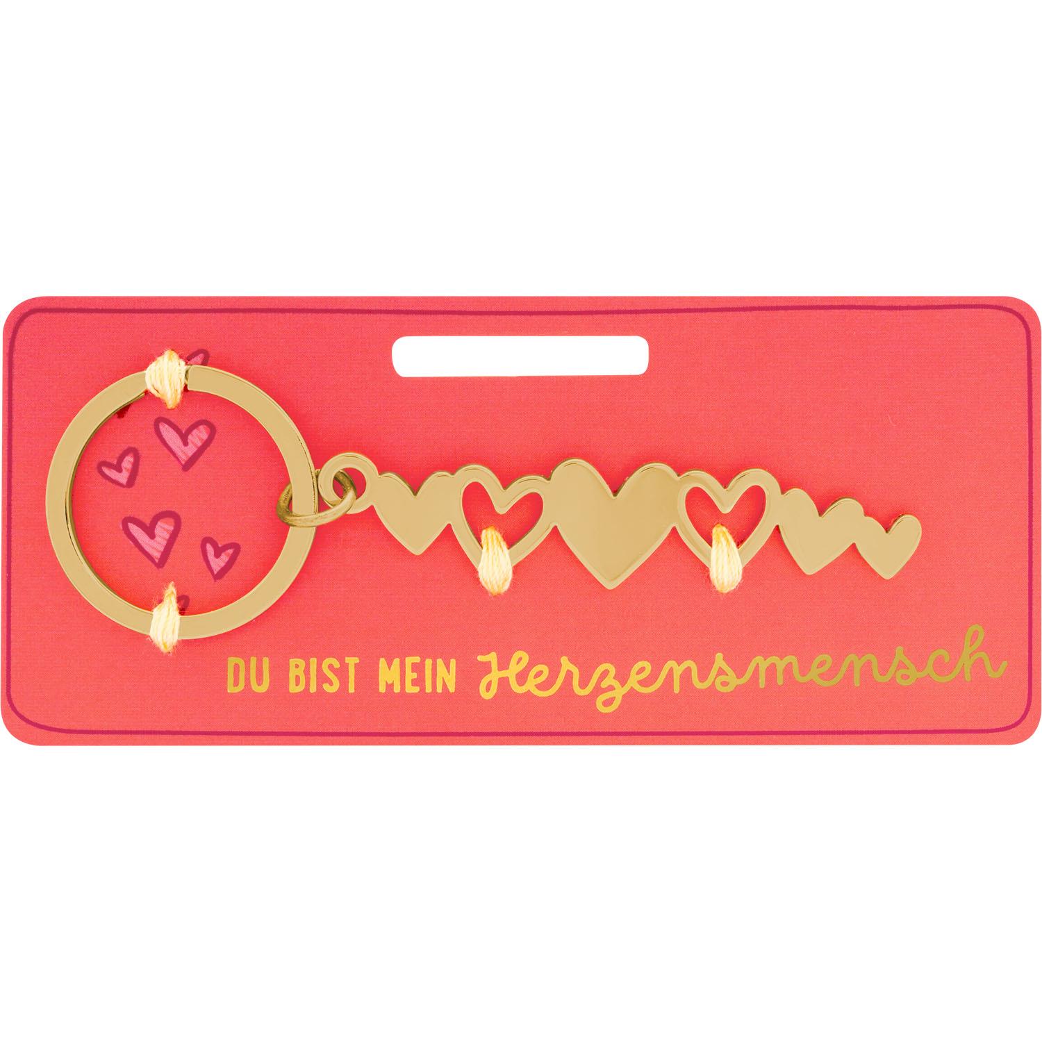 Goldfarbener Herzanhänger-Schlüsselring auf pinker Karte.