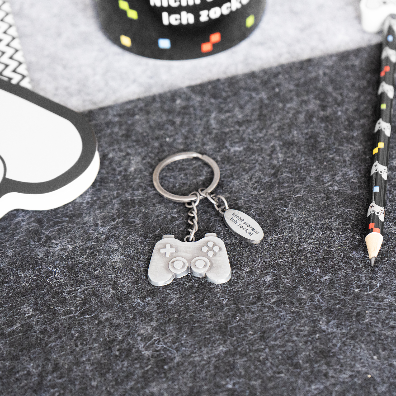 Silberner Schlüsselanhänger in Controller-Form mit kleinem Textschild