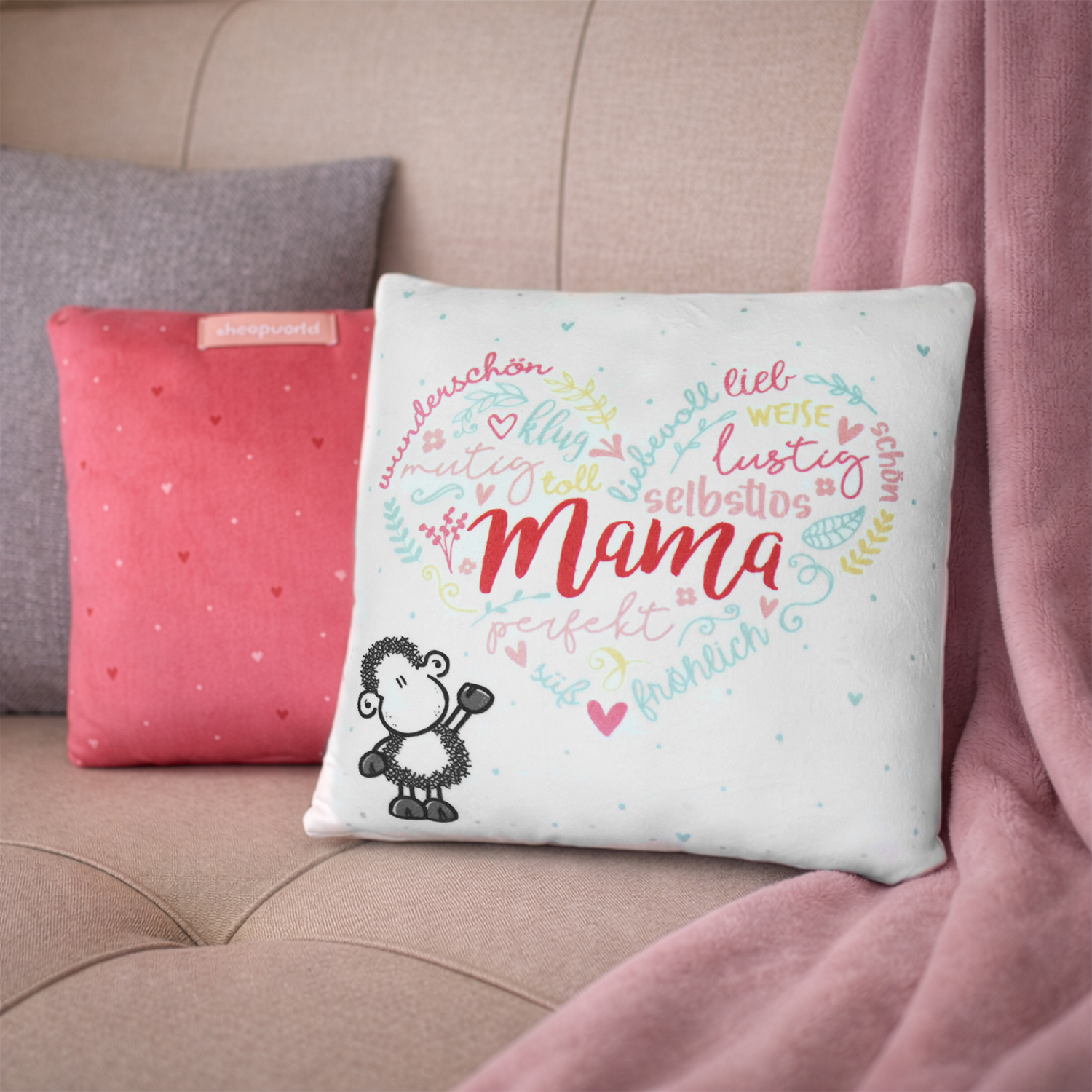Weißes Plüschkissen mit Herz-Wort-Motiv 'Mama' und kleinem Schaf.