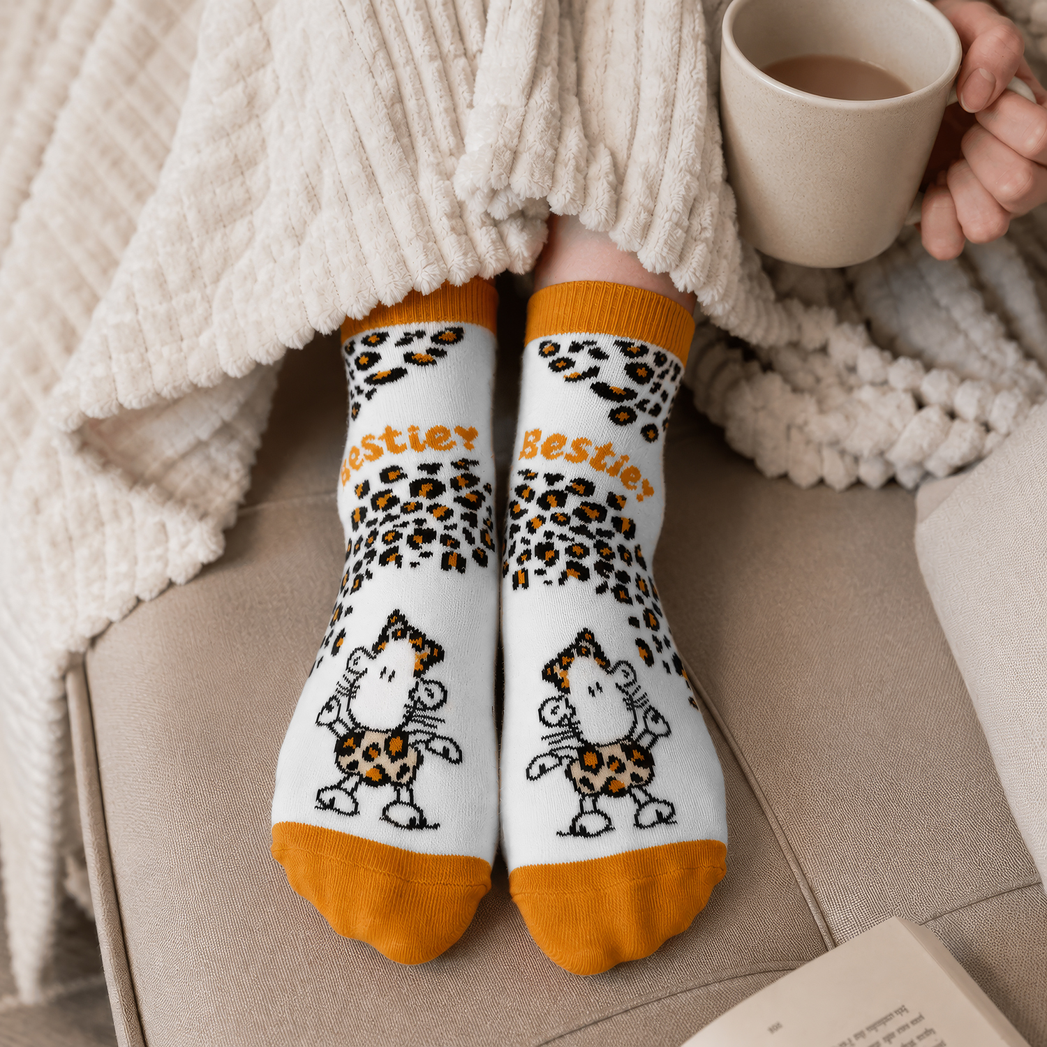 Weiße Socken mit Leopardenmuster und Schäfchen-Motiven, orange Bündchen.